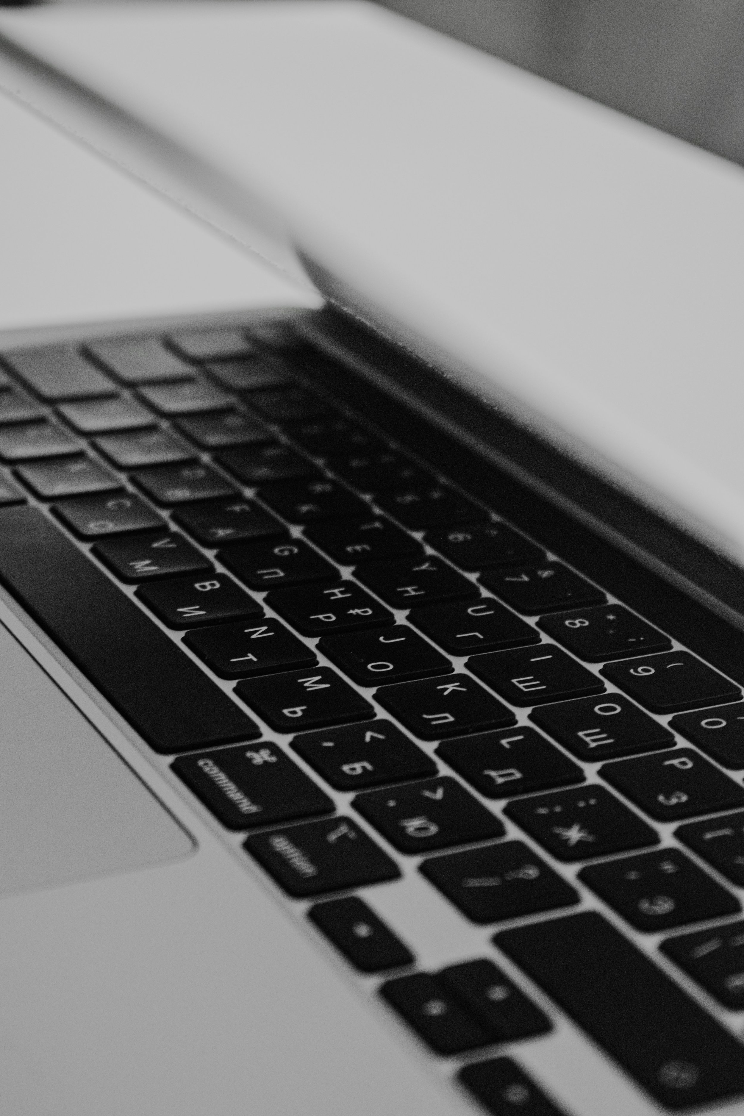 Close-up of a laptop keyboard in black and white with the screen partially visible.