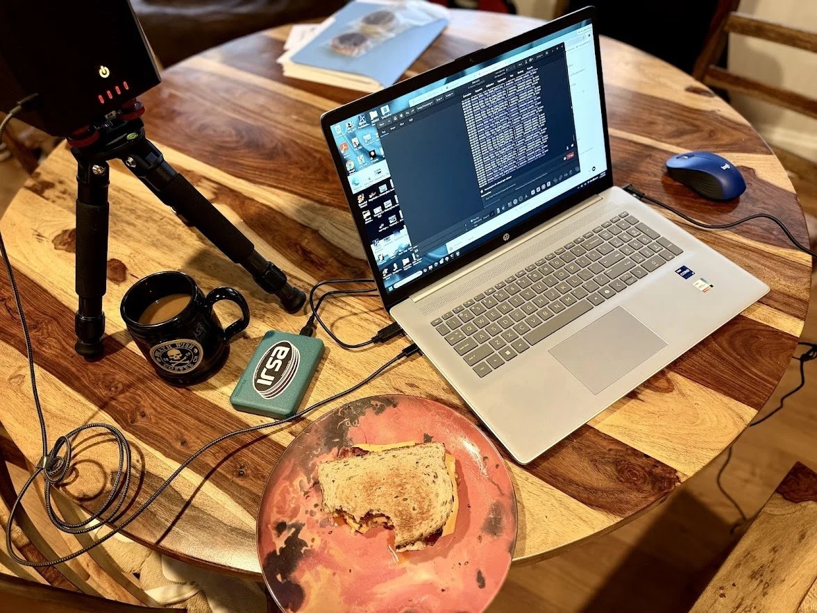 Laptop and sandwich on a wooden table.