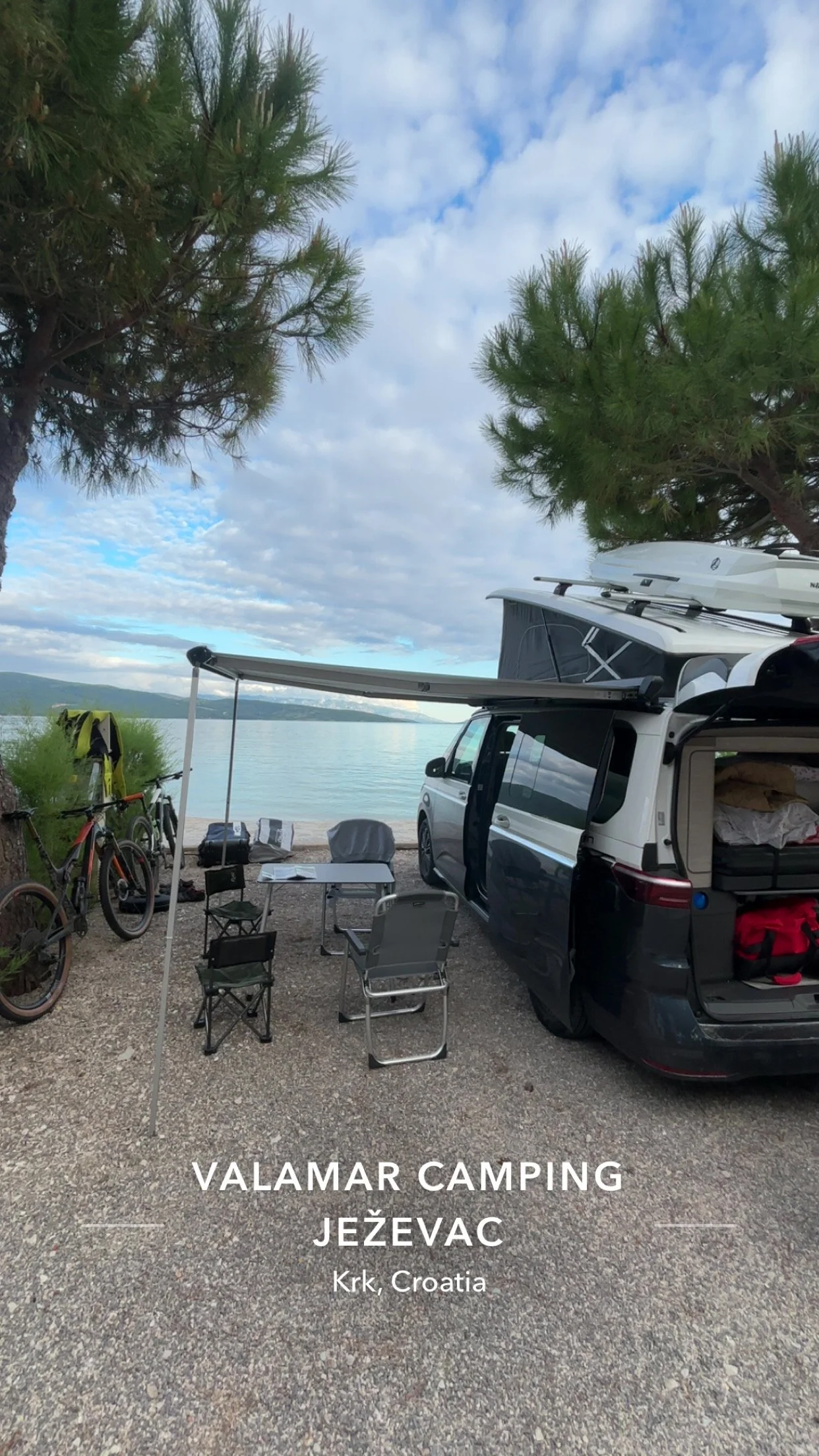 Camping setup by the lake with a van, bicycles, chairs, and trees at Valamar Camping Ježevac in Krk, Croatia.