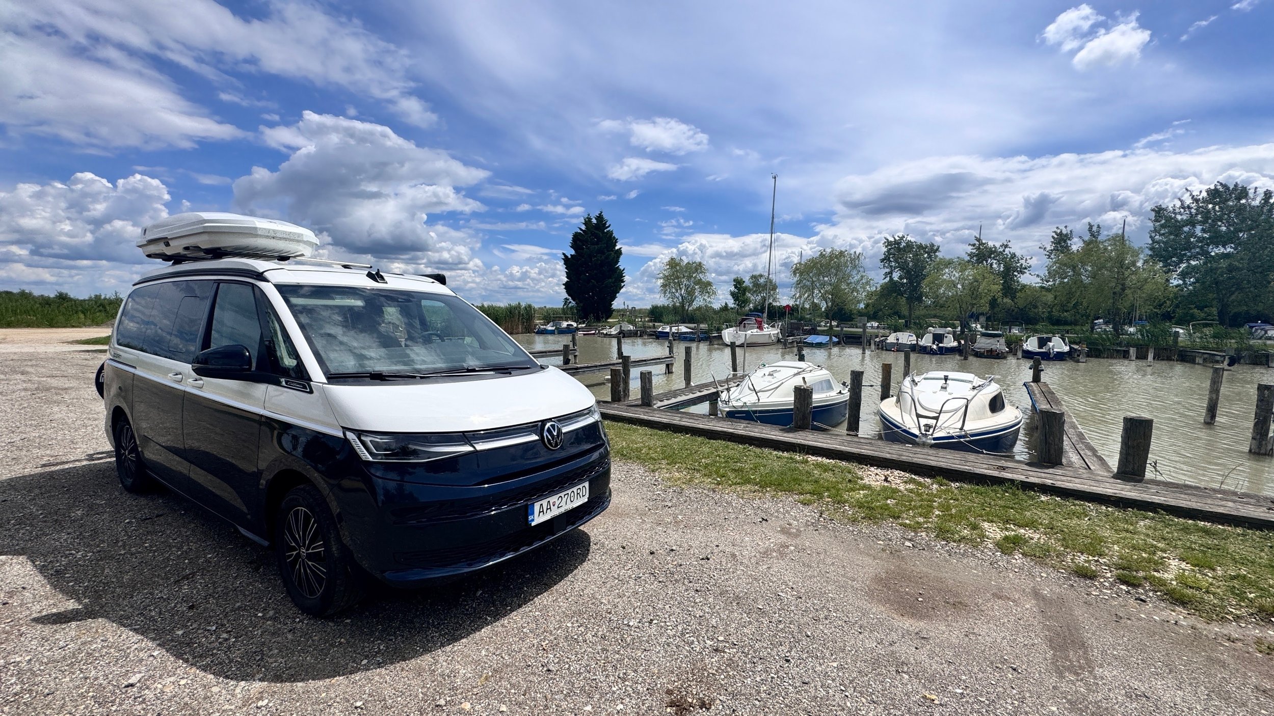 VW California zaparkovaný pri jazere a prístave s loďami