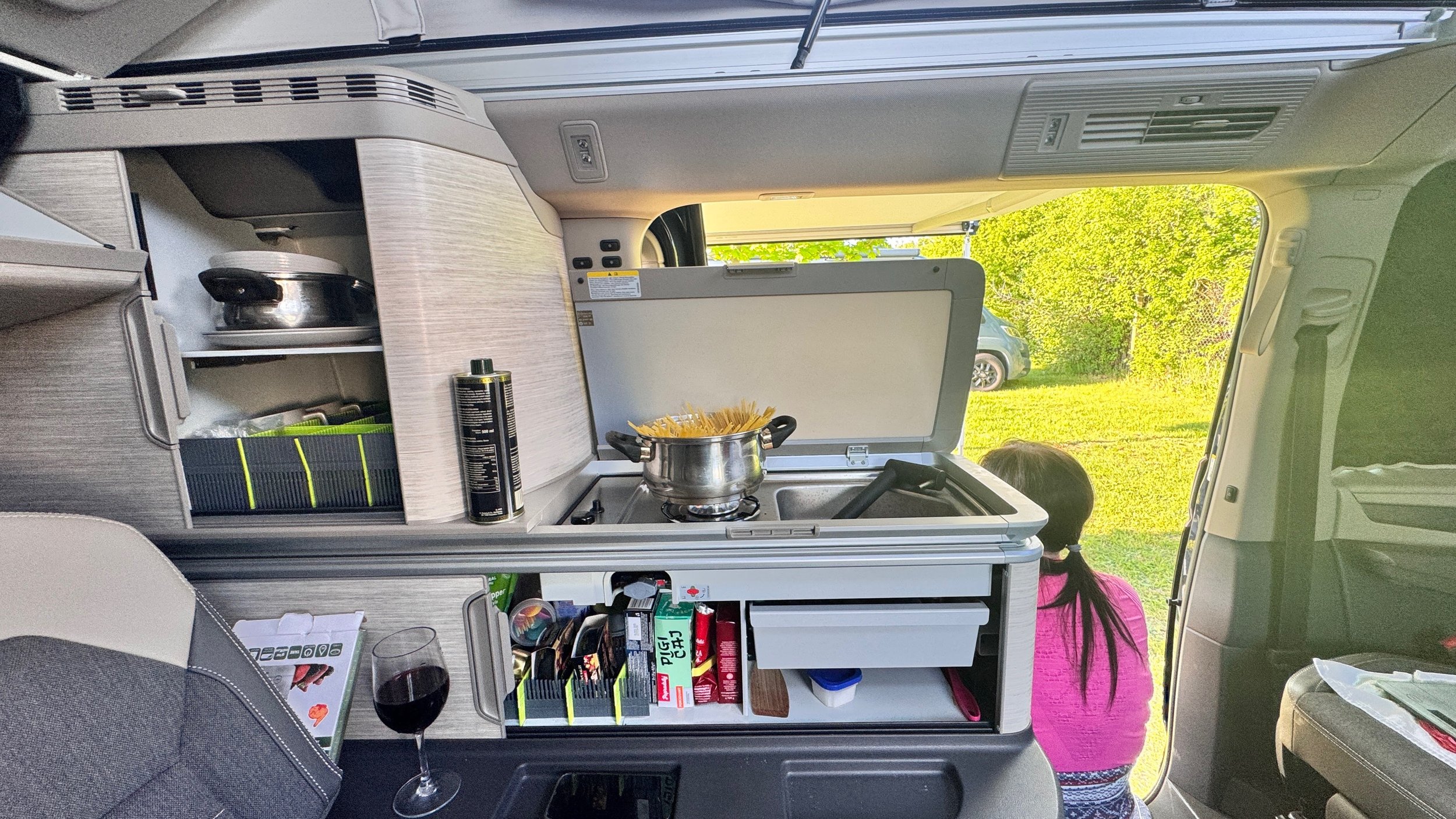 Interiér Volkswagen California s kuchynkou a otvorenými dverami do prírody