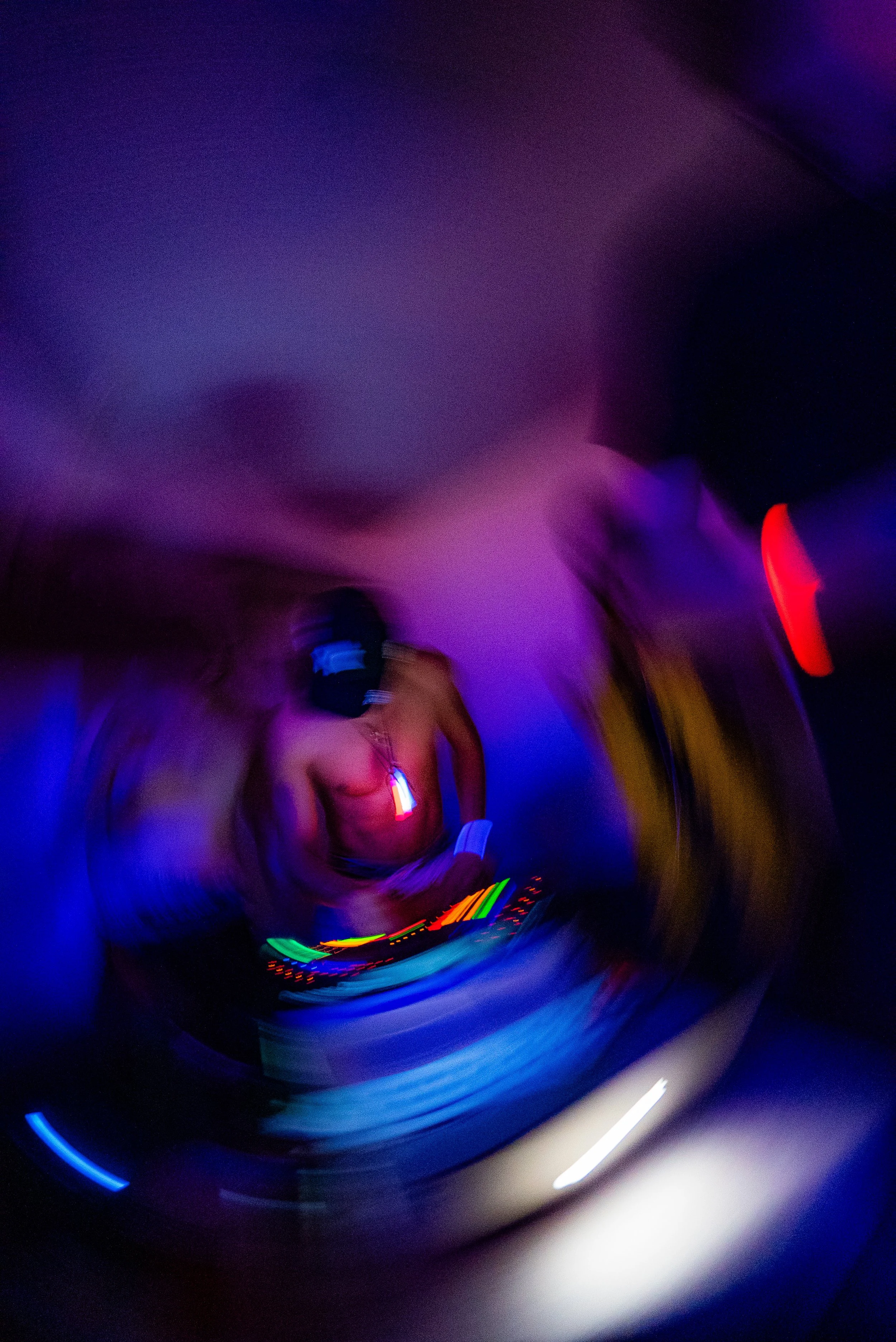 A DJ performing at a nightclub surrounded by colorful lights, with motion blur creating a swirling effect.