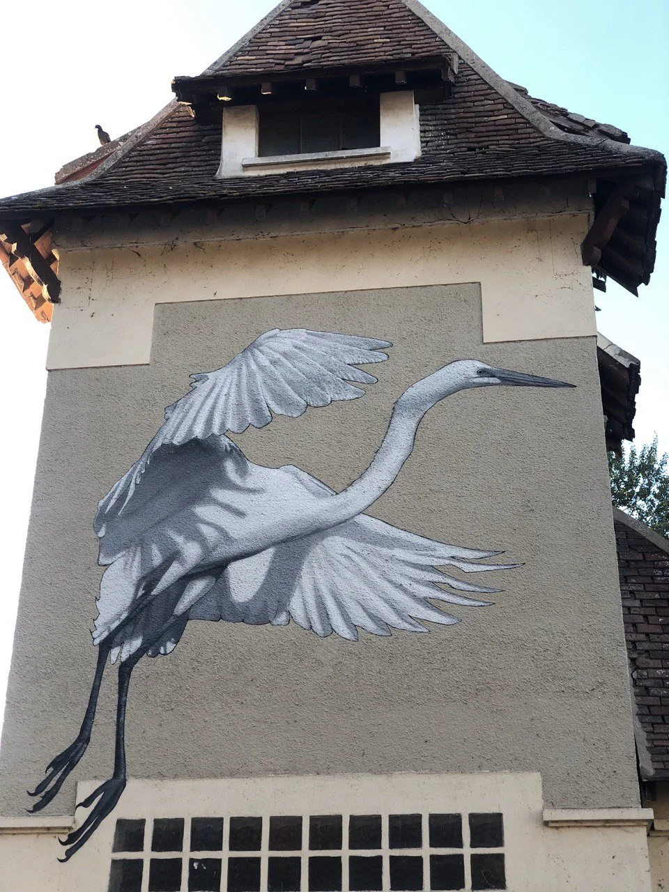 Détail d’une aigrette blanche aux ailes déployées, peinte à l’acrylique sur un support dont la teinte d’origine a été préservée.
