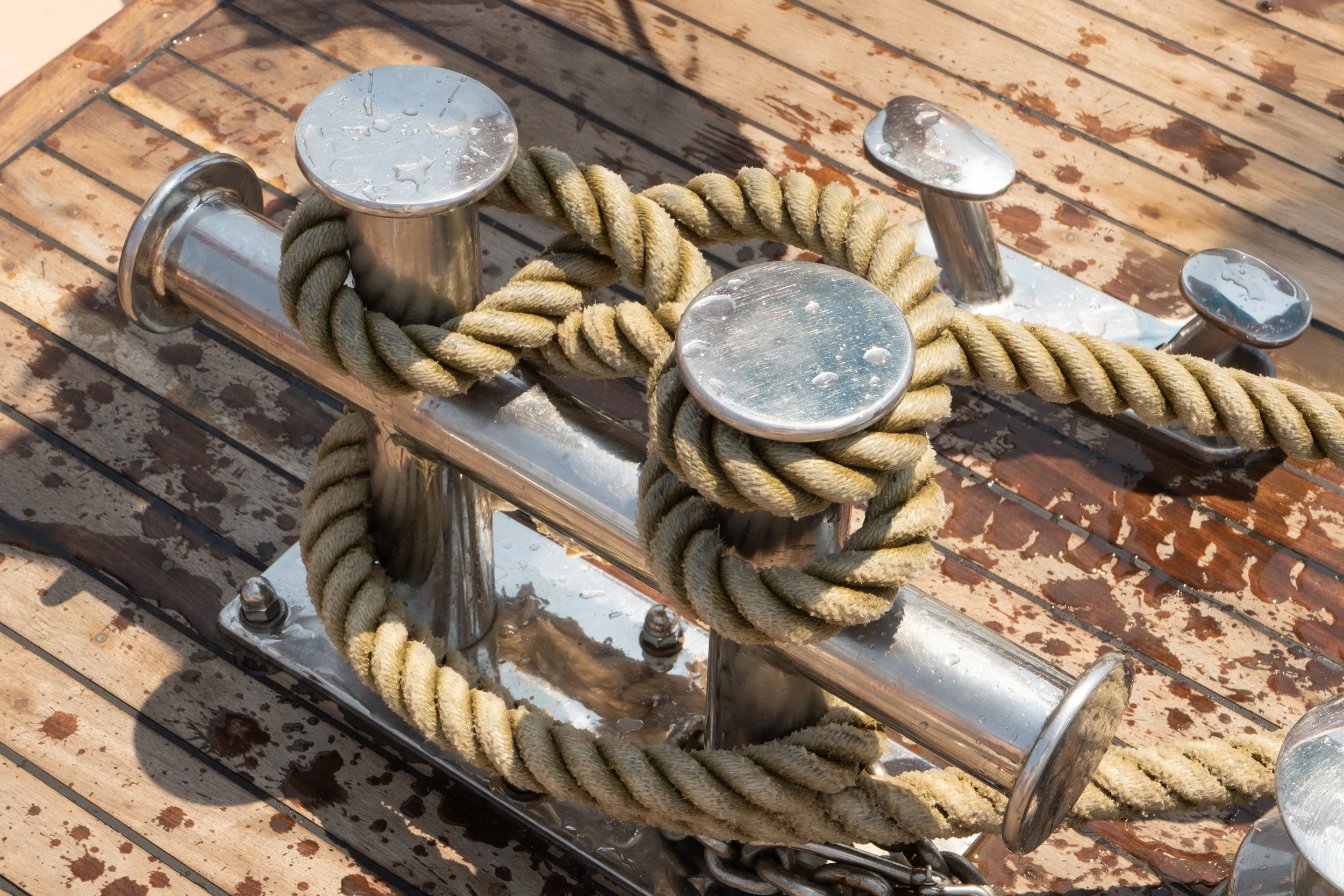Seilklemme und Anker auf einem Holzdeck, mit Wassertröpfchen auf den Oberflächen