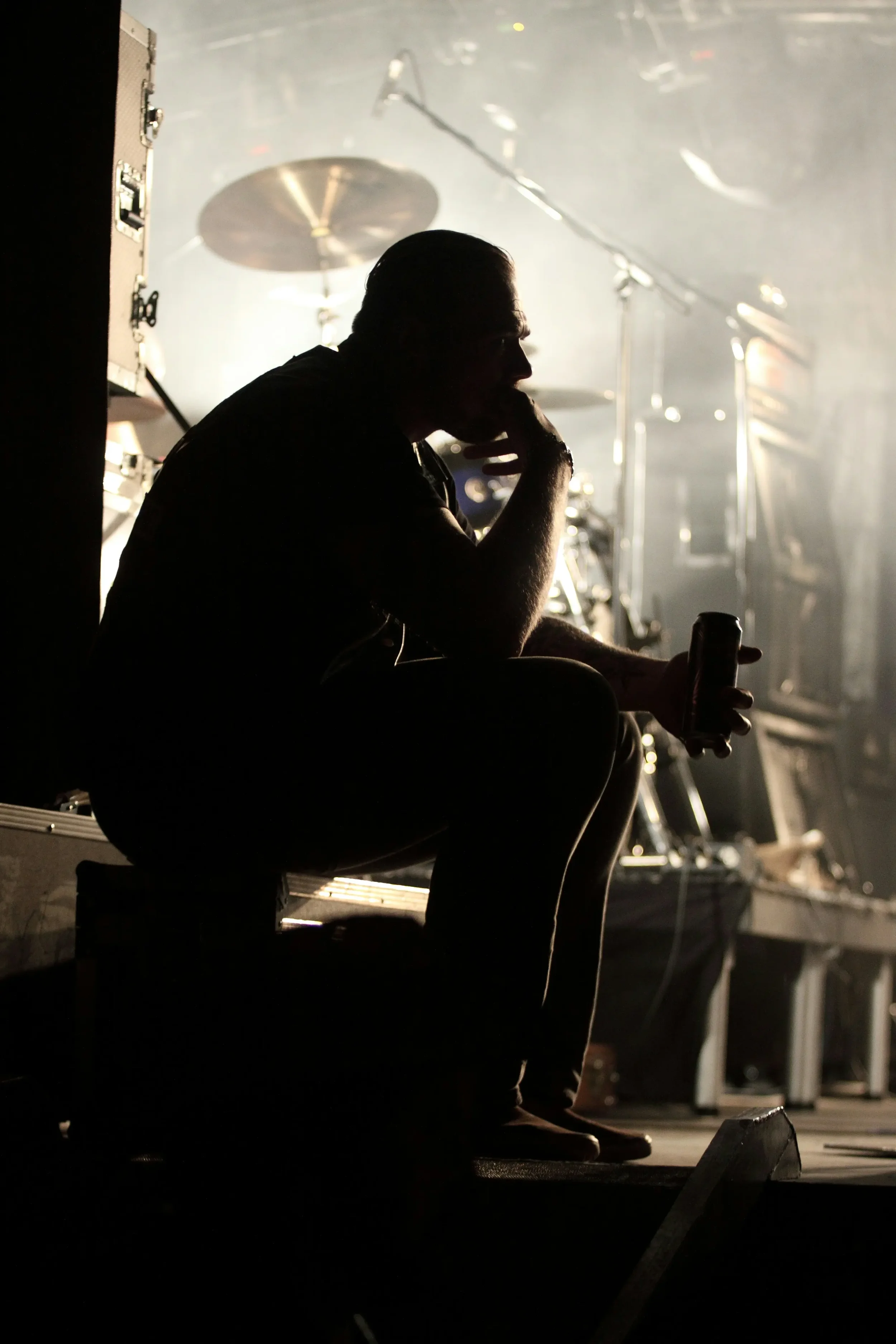 Musician sitting backstage beside a drum set, resting and thinking before performing — therapy for artists New York City