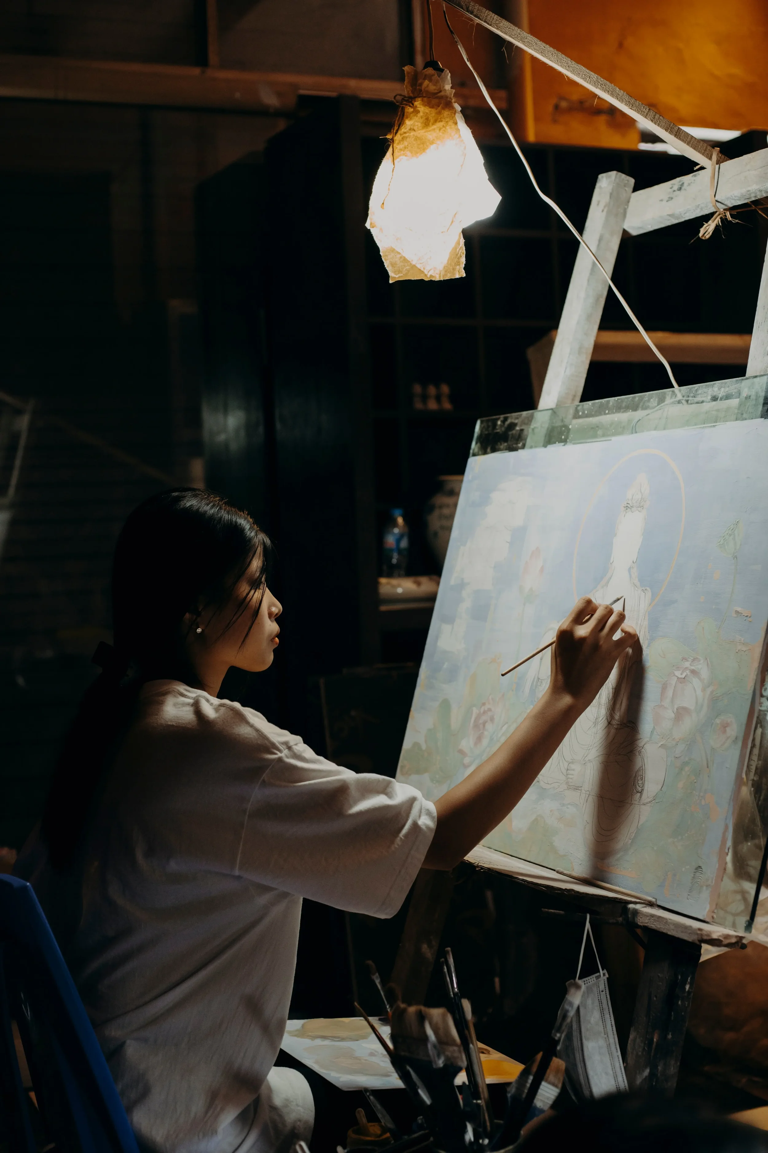 Painter working alone in a dim studio, reflecting the inner experience explored in therapy for artists in New York City