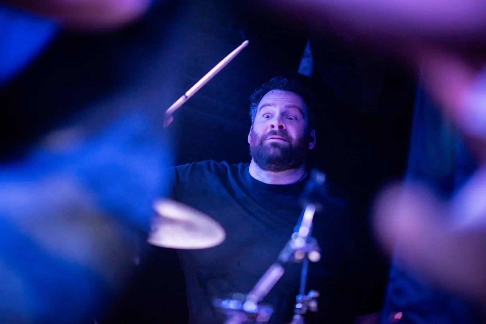 SOMB Scared of My Brother Arthur Kinnear-Kirkwood playing drums in a dark room with blue and purple lighting.