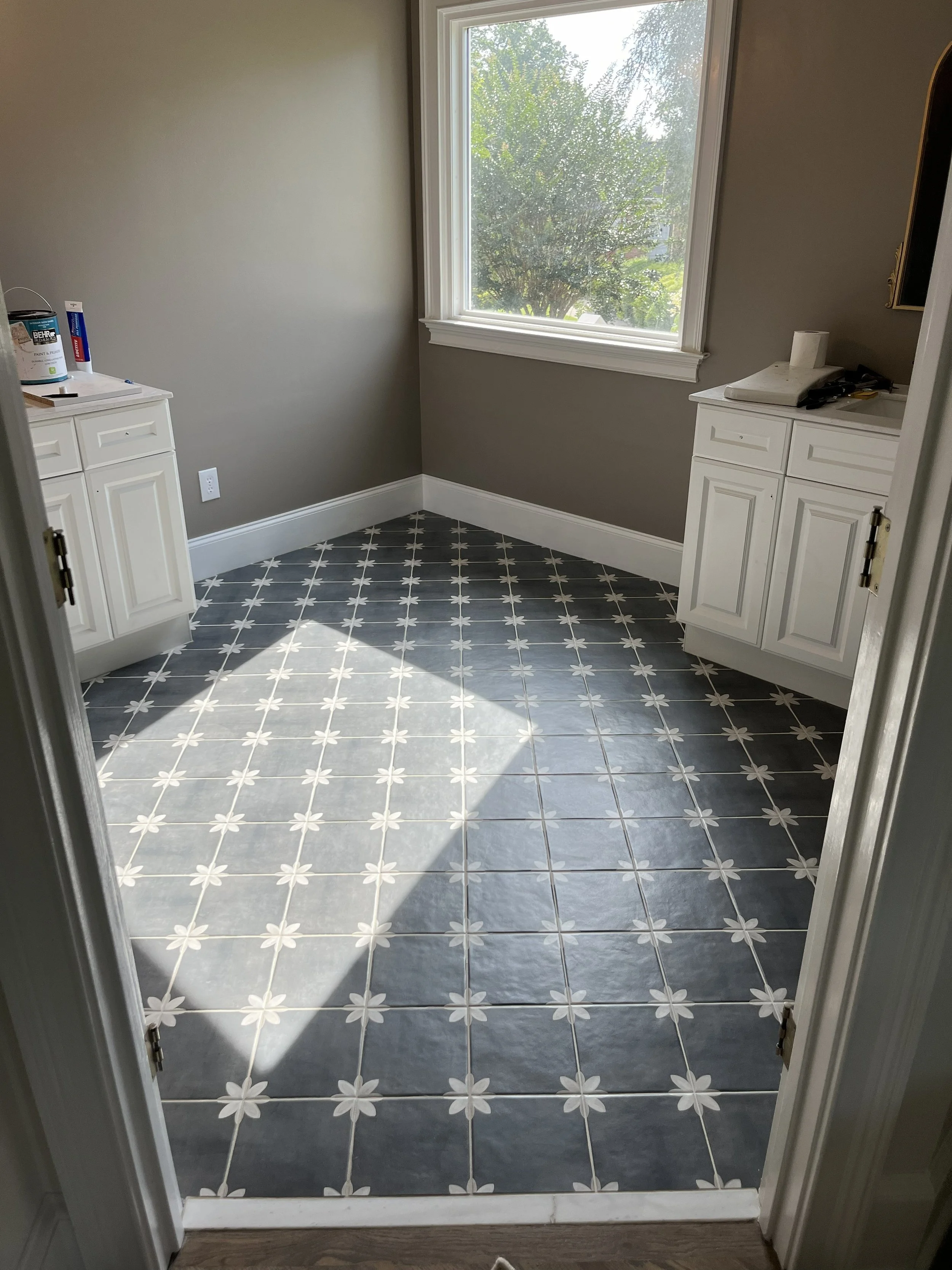 Custom floor tile installation featuring charcoal-gray square tiles with delicate white starburst accents, creating a timeless geometric pattern that beautifully complements the white cabinetry.