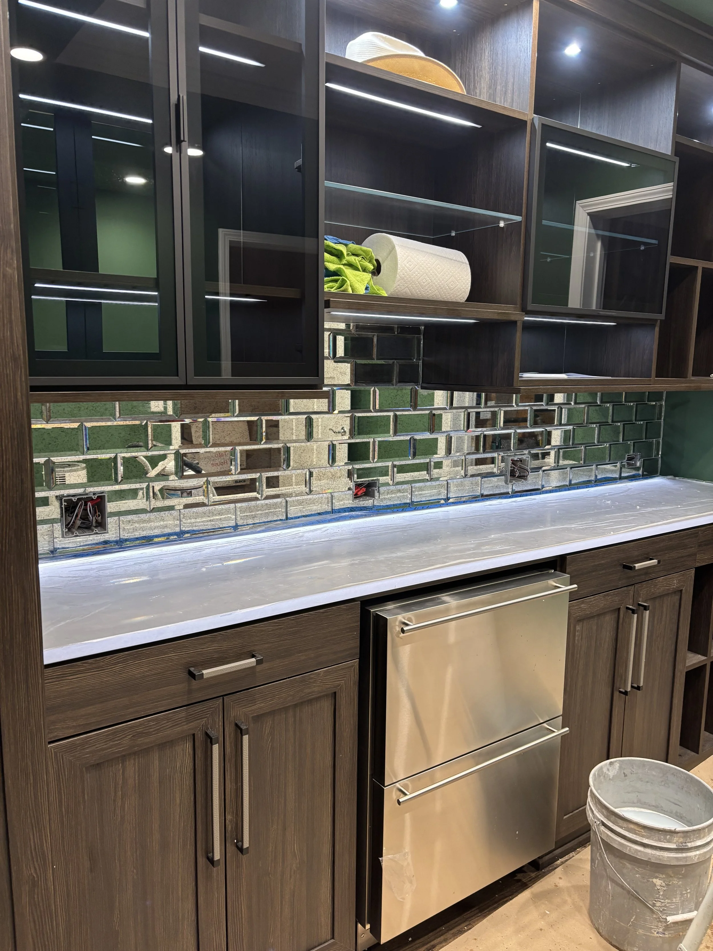 Custom glass tile backsplash featuring a reflective mosaic design that beautifully complements the dark wood cabinetry, adding depth, contrast, and a modern touch to the space.
