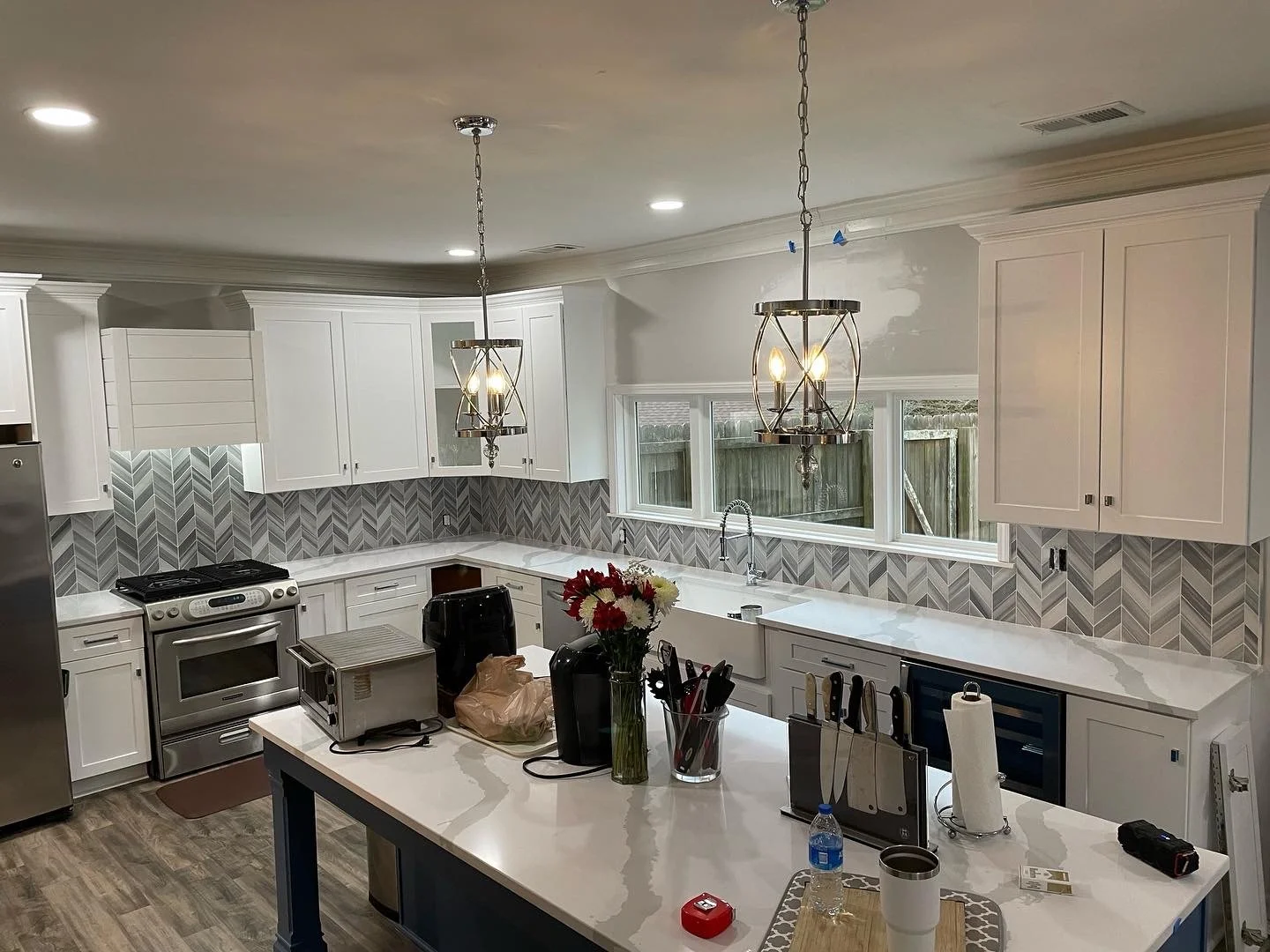 Custom kitchen backsplash featuring a modern gray and white chevron tile pattern, adding texture, dimension, and an elegant contrast to the white cabinetry and countertops.