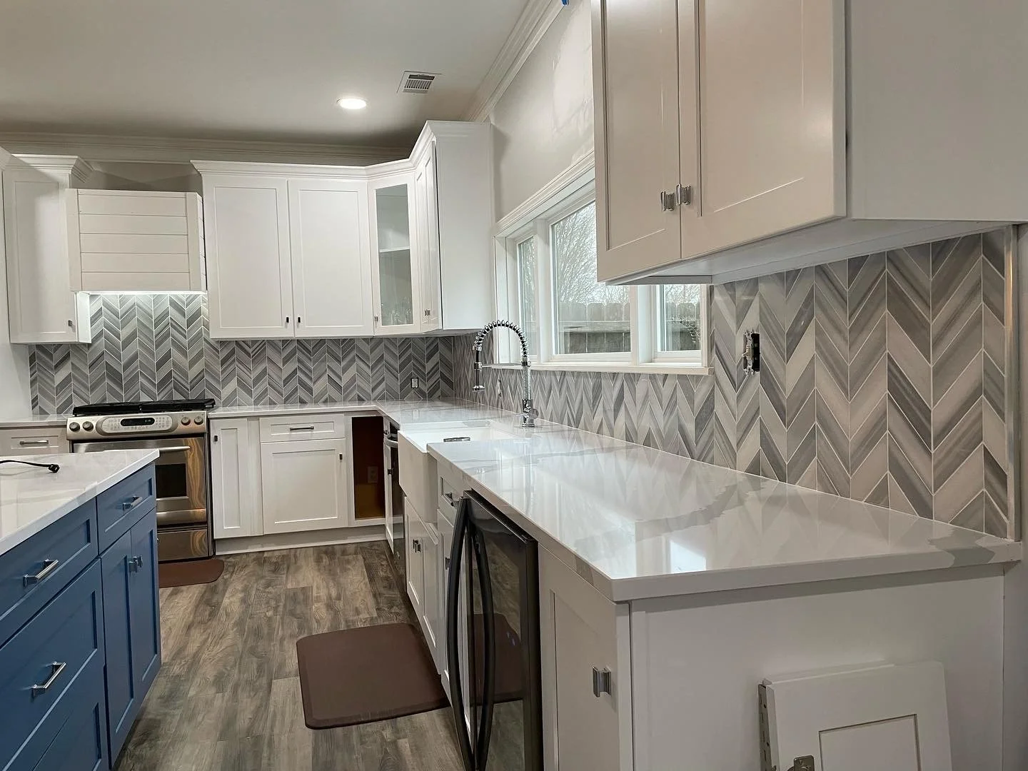 Custom kitchen backsplash featuring a modern gray and white chevron tile pattern, adding texture, dimension, and an elegant contrast to the white cabinetry and countertops.