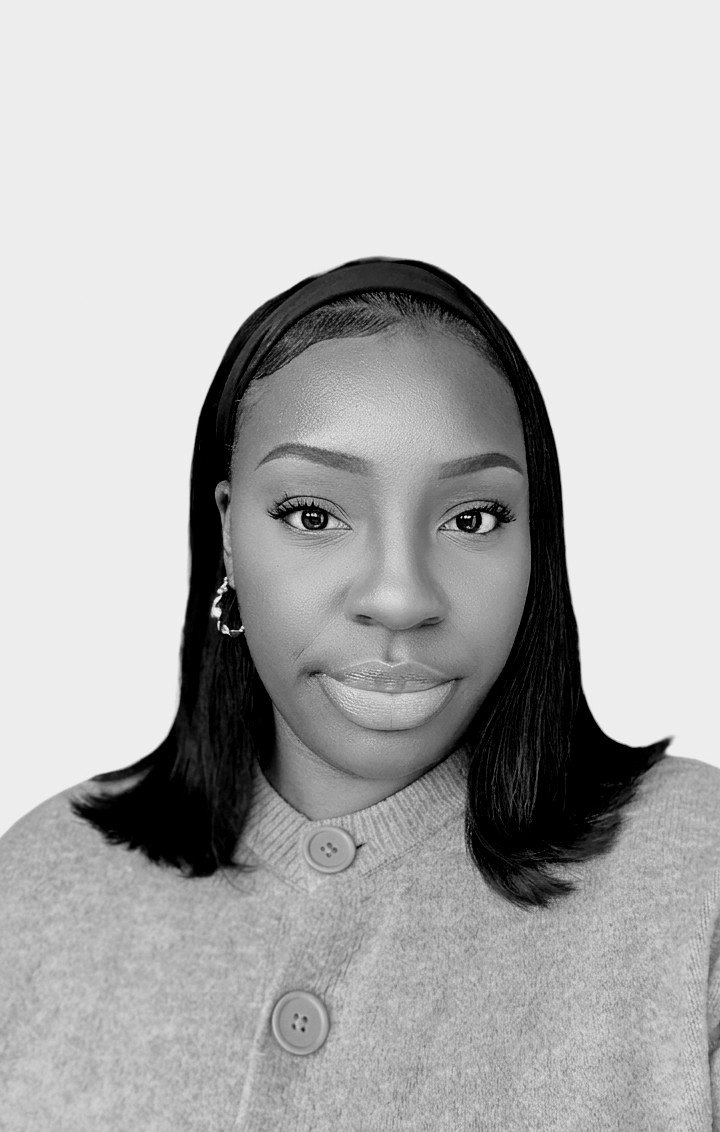 Black and white portrait of a woman with shoulder-length hair, wearing a headband, earrings, and a button-up sweater.