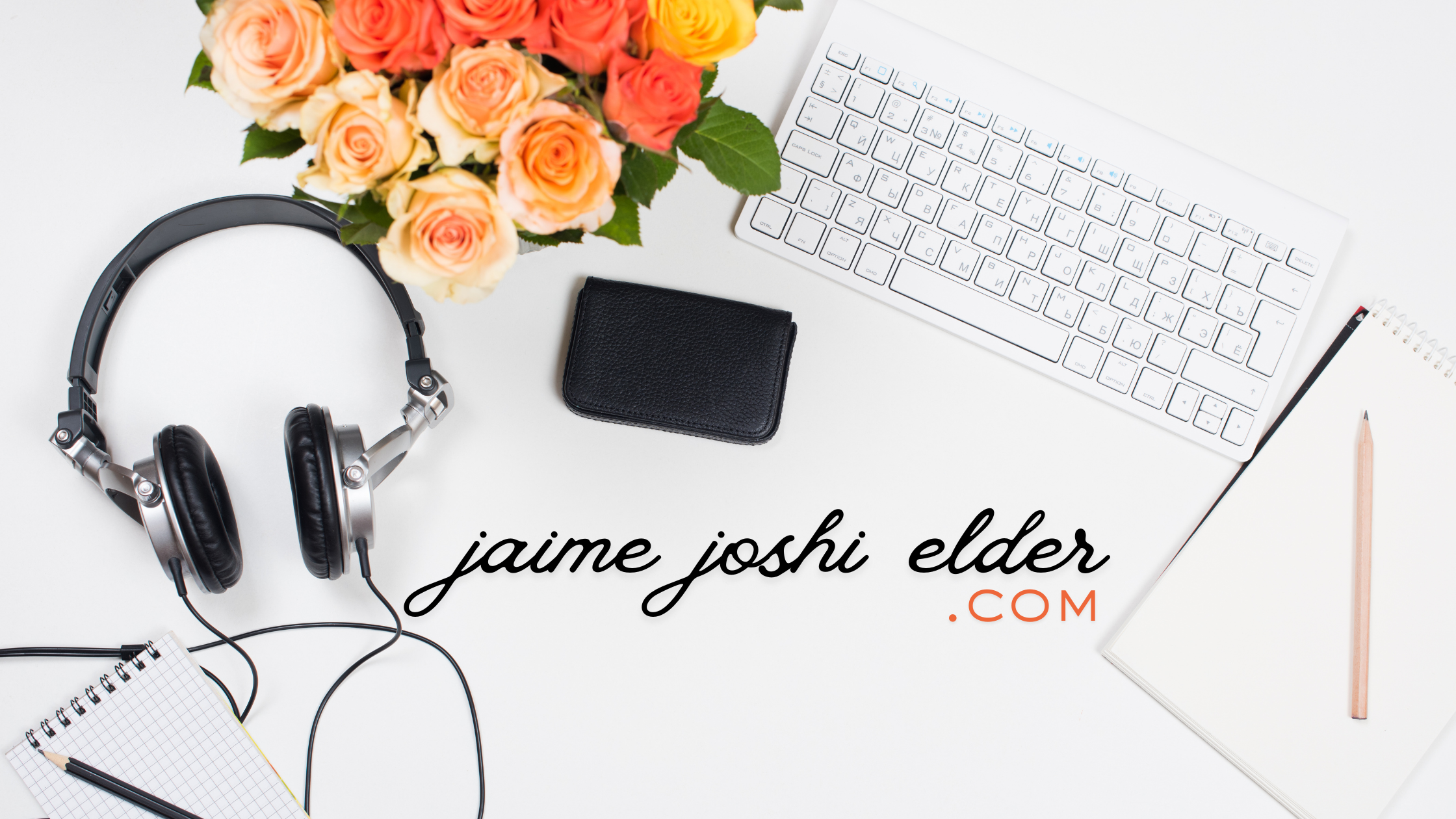 Flat lay of a white workspace with a bouquet of pink, peach, and yellow roses, a pair of black and silver headphones, a black wallet, a white wireless keyboard, a spiral notebook with a pencil, and a white notepad with a pink pencil. Text reads "jaime joshi elder .COM" in black and orange.