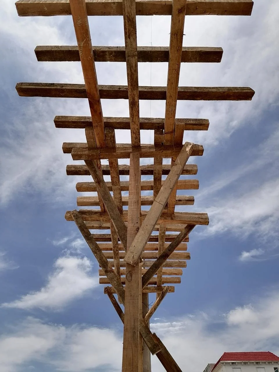 Estructura de madera en construcción contra el cielo nublado, vista desde abajo.
