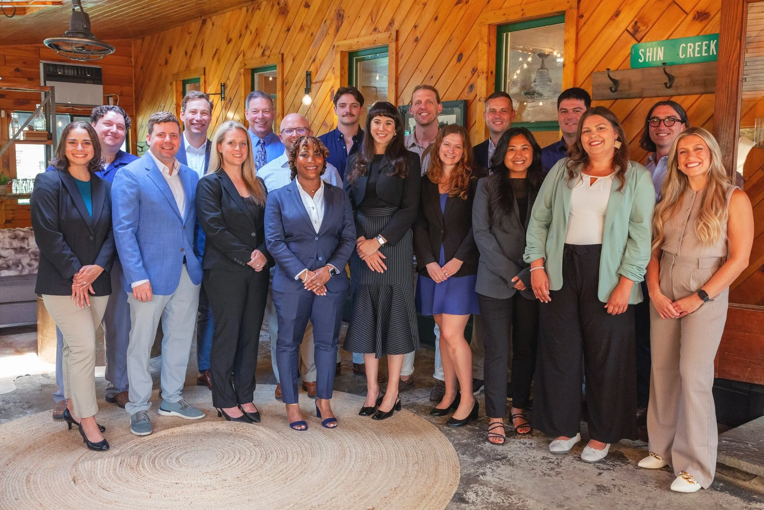 Group of financial advisors from Brooklyn fi dressed in business attire posing in a wooden restaurant or cafe with a