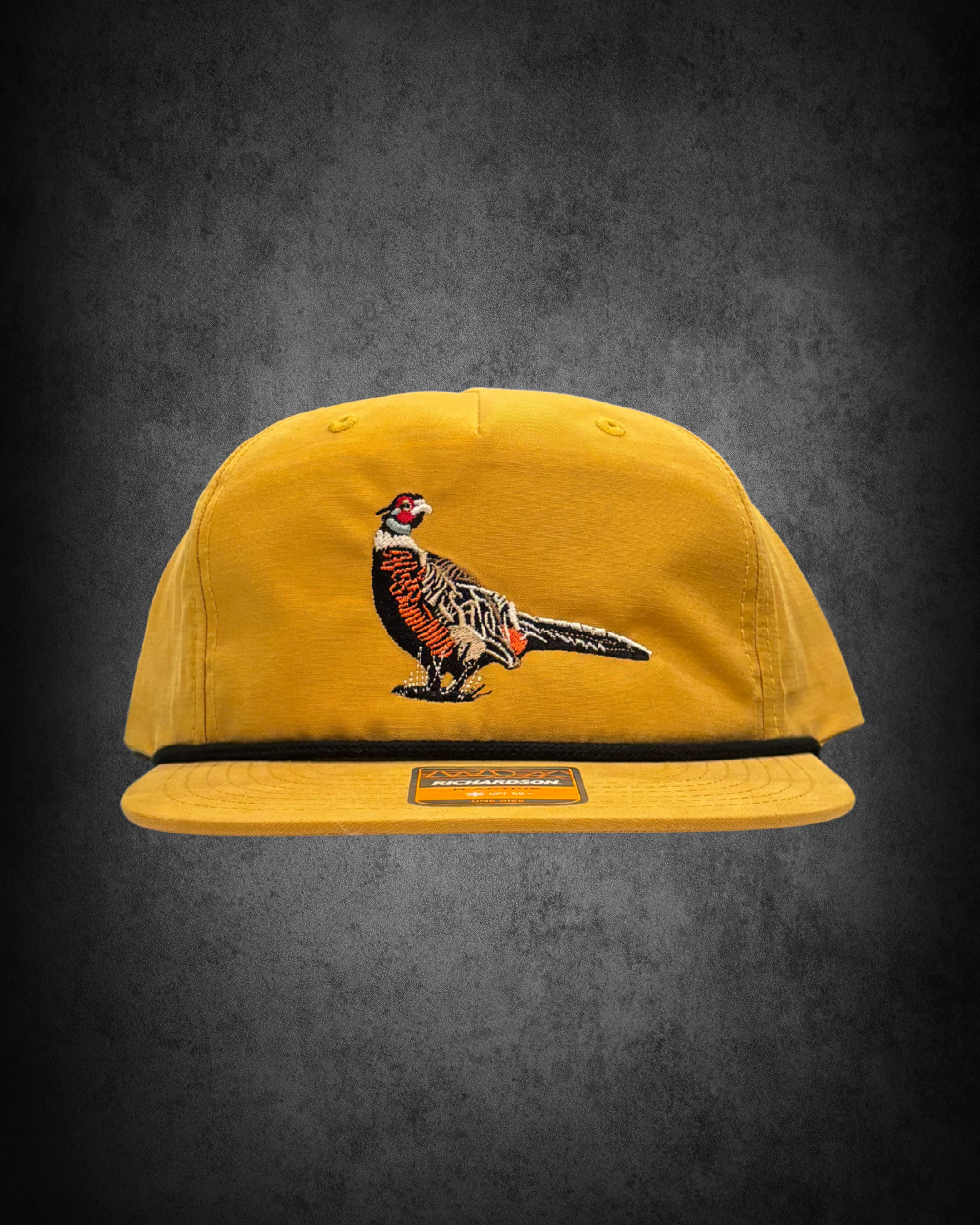 A yellow baseball cap with a colorful embroidered pheasant on the front, displayed against a dark background.