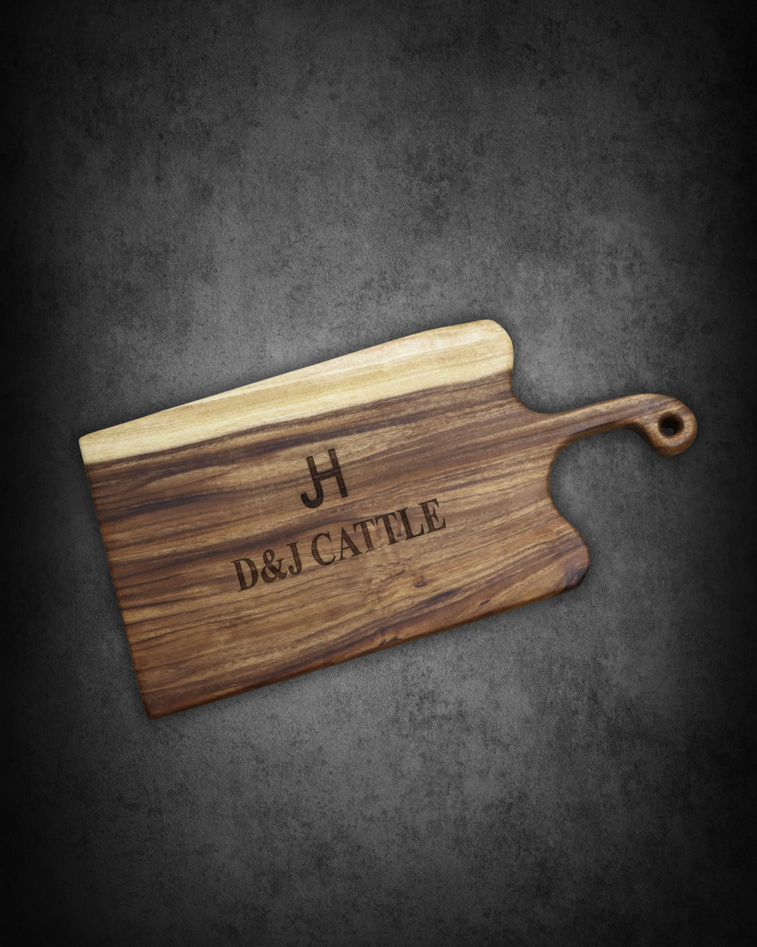 Close-up of a wooden cutting board with engraved text, set on a dark surface.