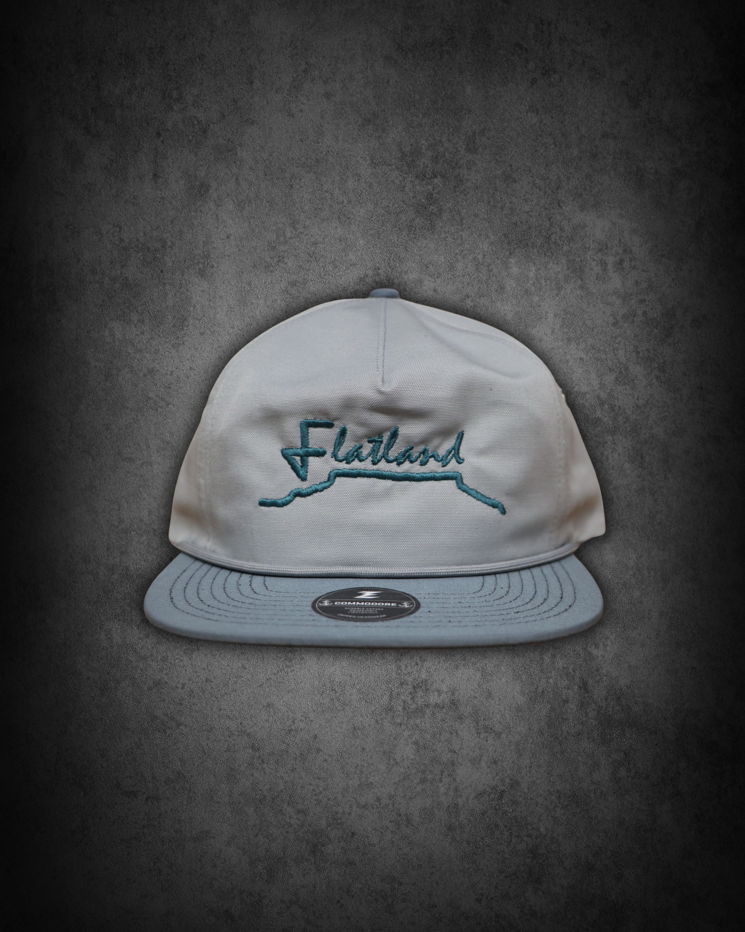 White baseball cap with blue embroidered text that reads 'Florida' and a stylized outline of the state. The cap is placed on a dark, textured surface.