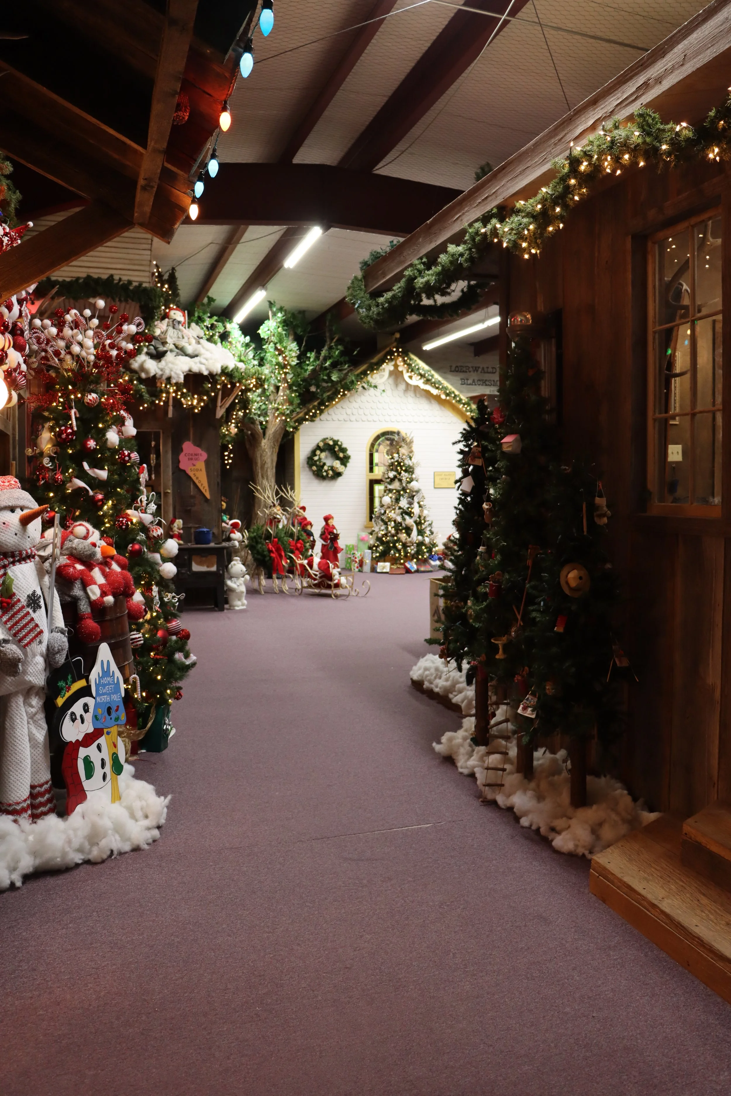 Christmas decorated indoor space with trees, snowman figures, and festive ornaments, featuring string lights and green garlands. The inside of H&R Manufacturing in Hereford, TX.
