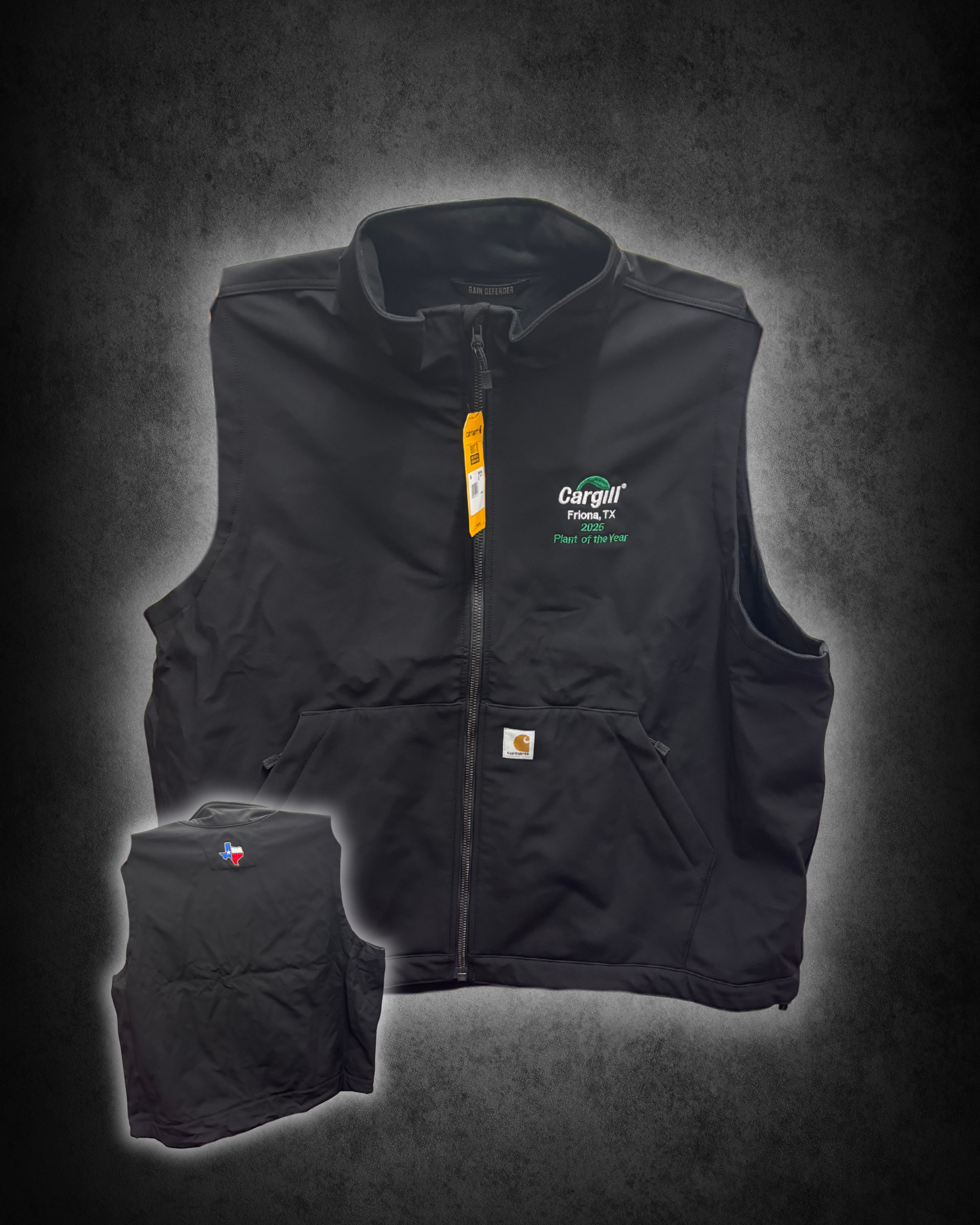 A black Carhartt vest with the Cargill logo and location embroidery, a yellow tag attached, and a small stitched Texas state flag patch on the sleeve, set against a dark textured background.