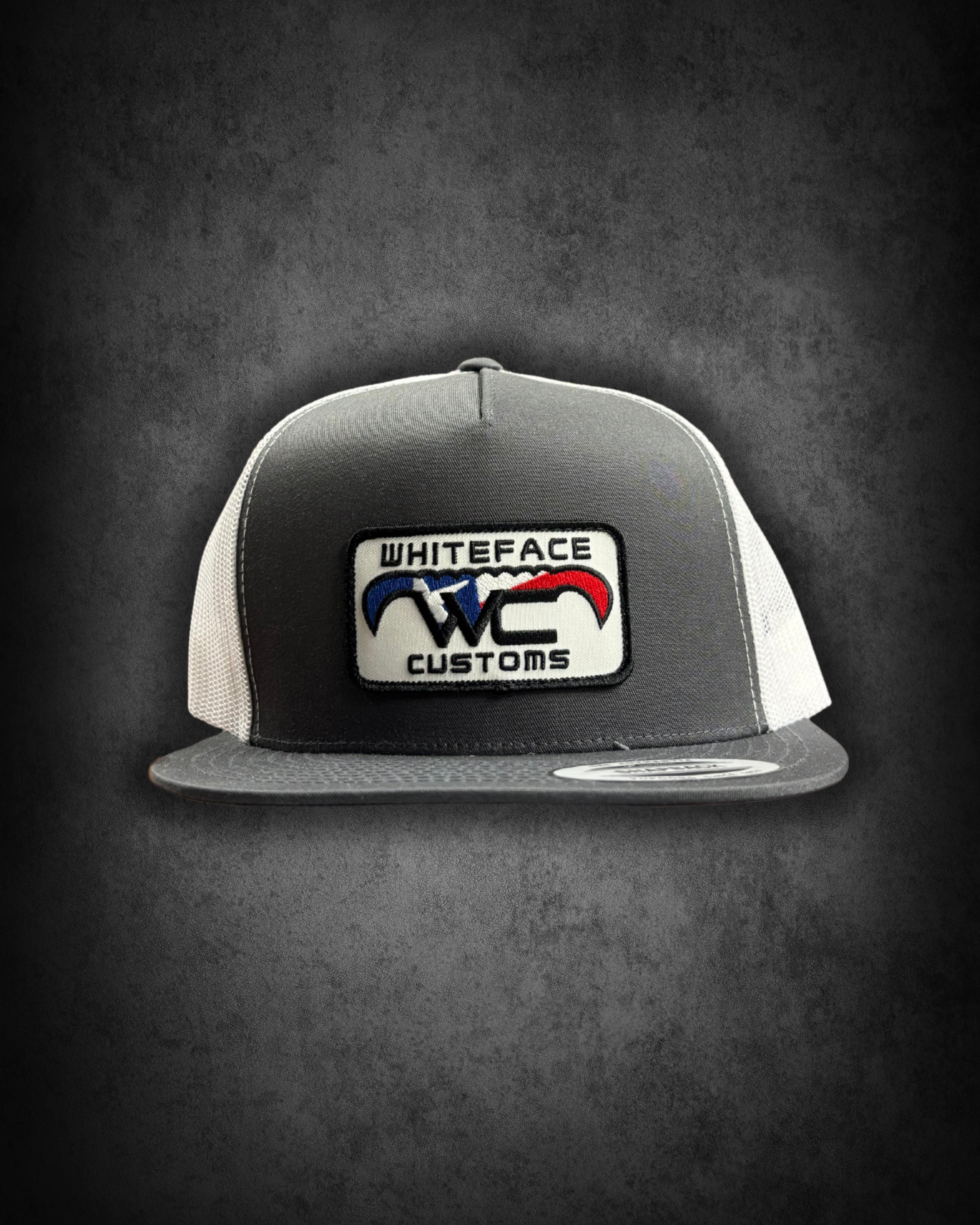 A gray and white baseball cap with a patch on the front that reads 'Whiteface Customs' and features a logo with red, white, and blue colors against a dark background.