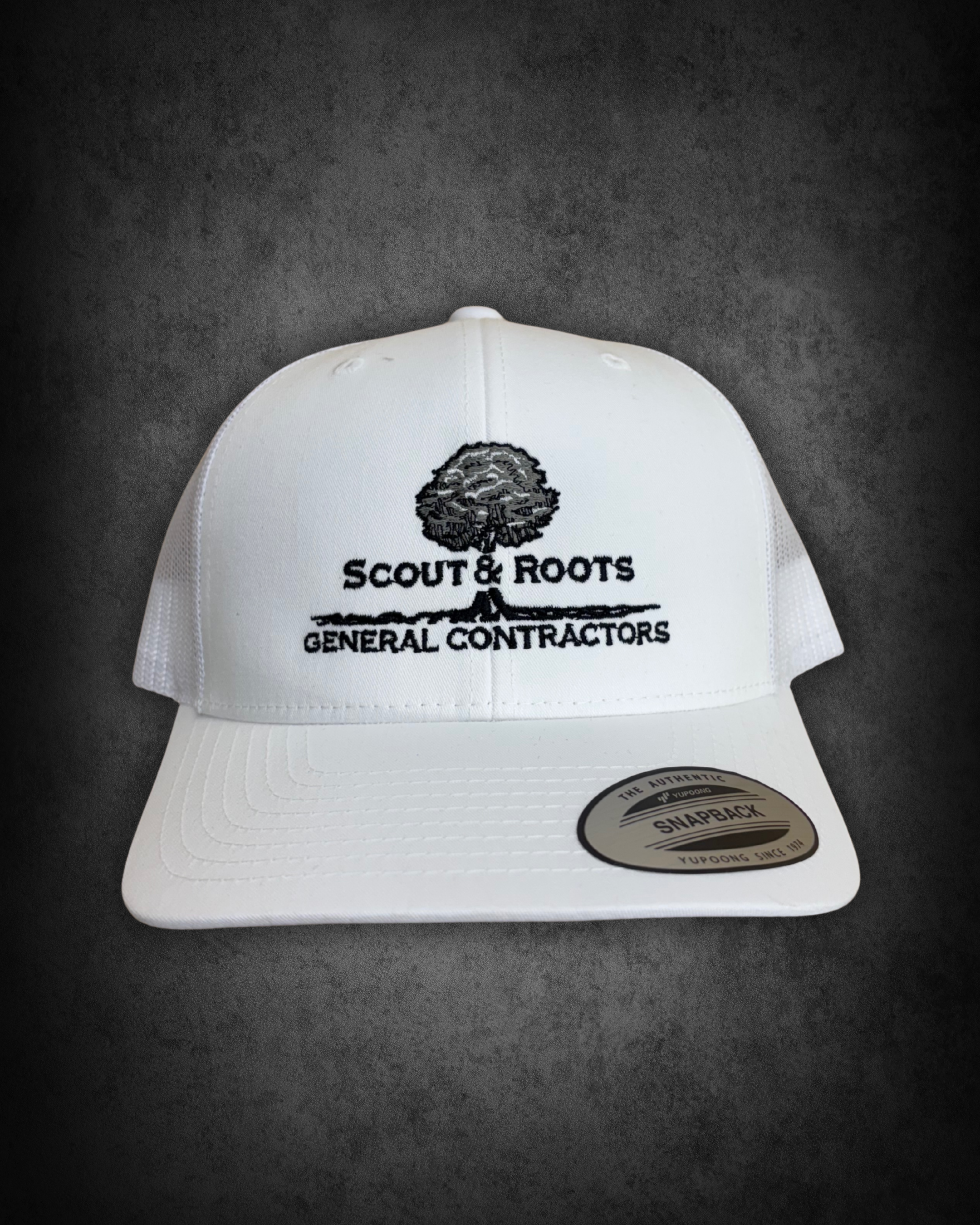 White baseball cap with embroidered logo and text, displayed on a dark surface. The logo is a tree with the text "Scout & Roots" underneath, and additional smaller text reading "General Contractors." There is also a sticker at the bottom of the cap t