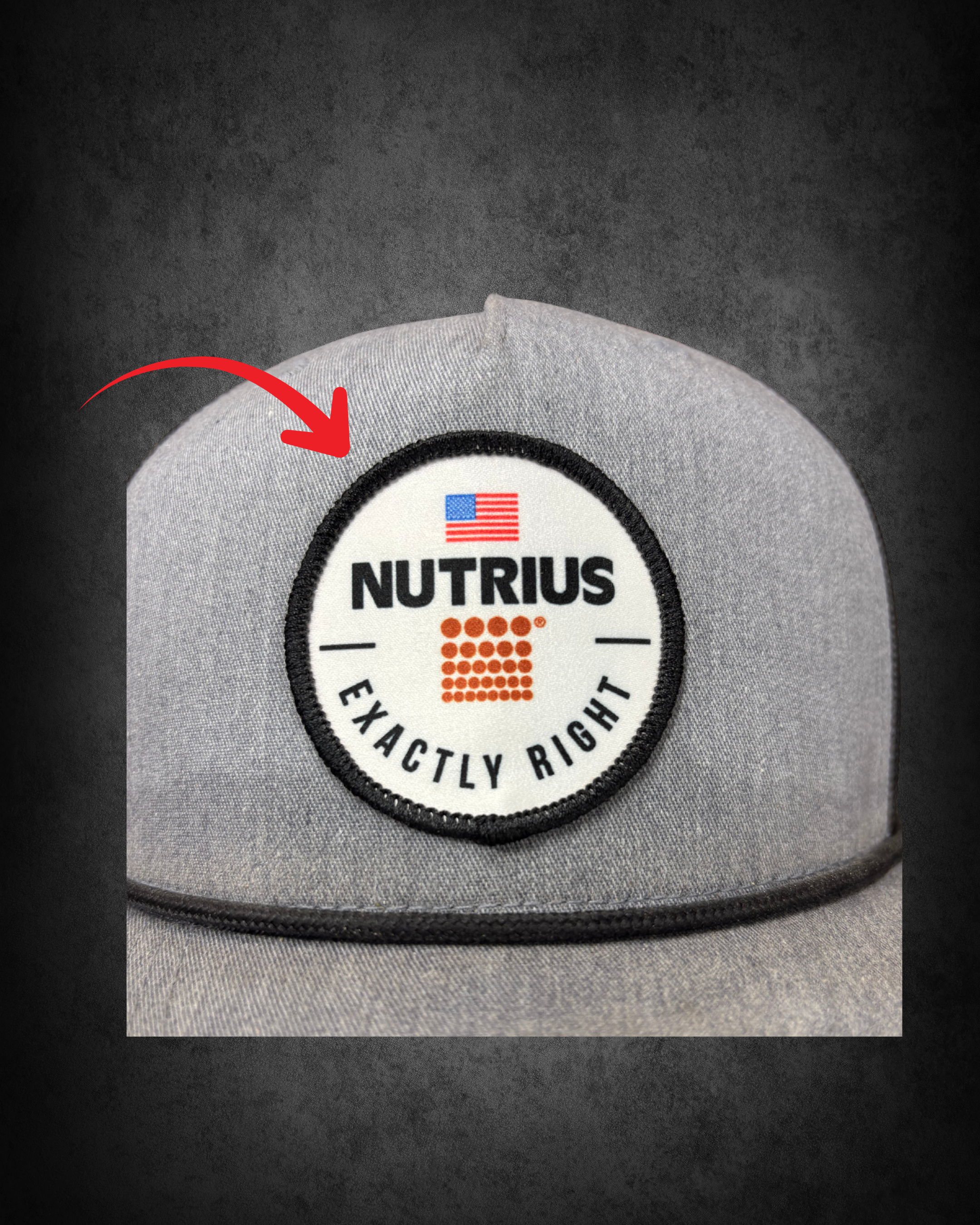 Close-up of a round patch with the Nutrius logo, featuring a stylized American flag, on gray fabric with black stitching, on a dark background.