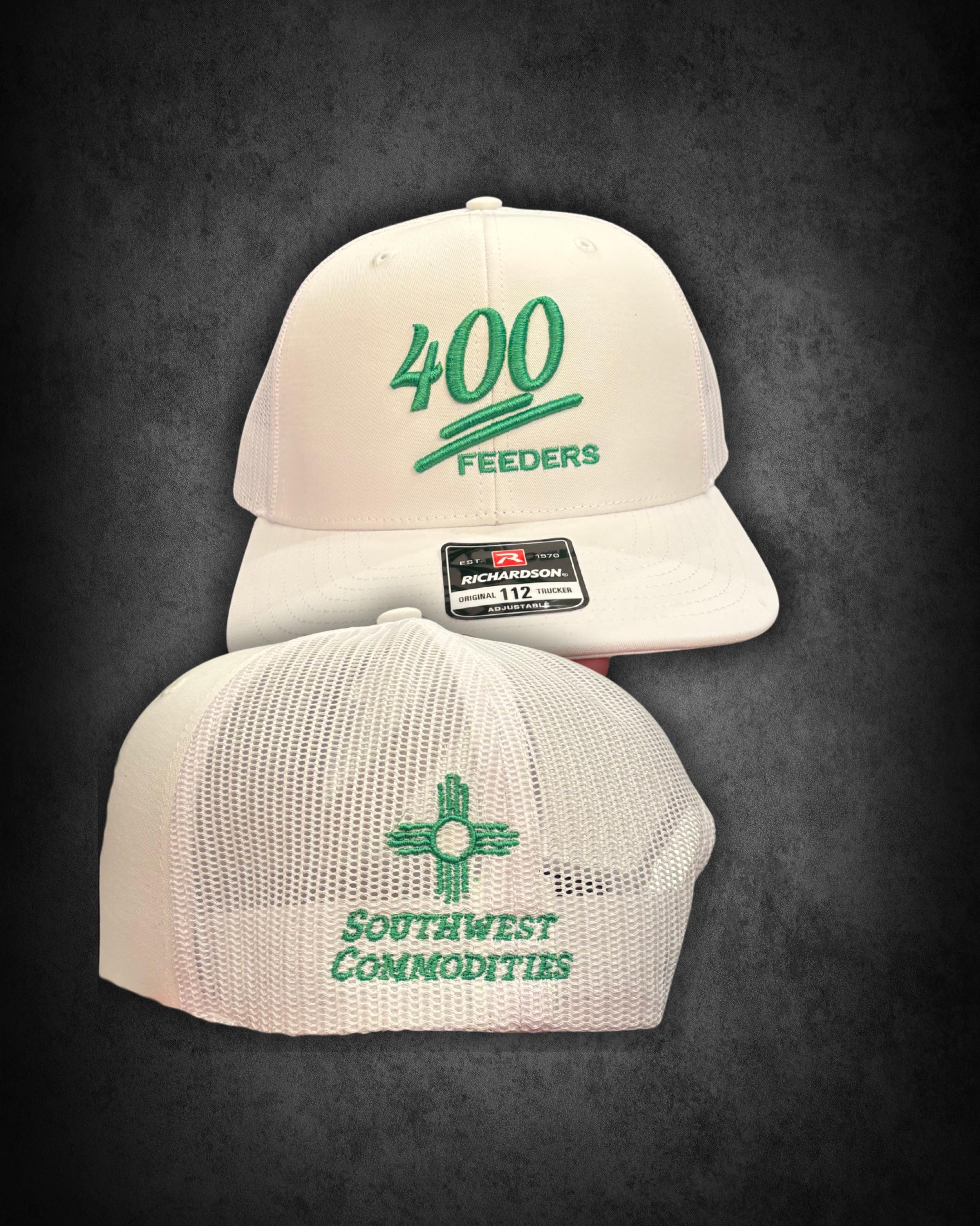White baseball cap with green embroidery that reads '400 FEEDERS', a black and white Richardson tag on the brim, and a mesh back, placed on a dark surface.