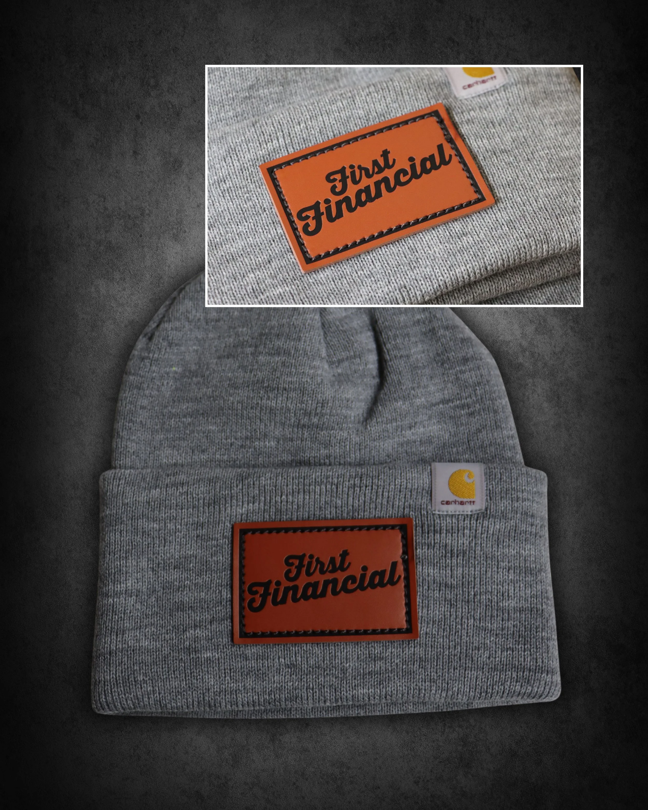 Gray fabric clothing with a leather patch that reads "First Financial" in black script, and a small Carhartt logo tag in white with a yellow emblem.