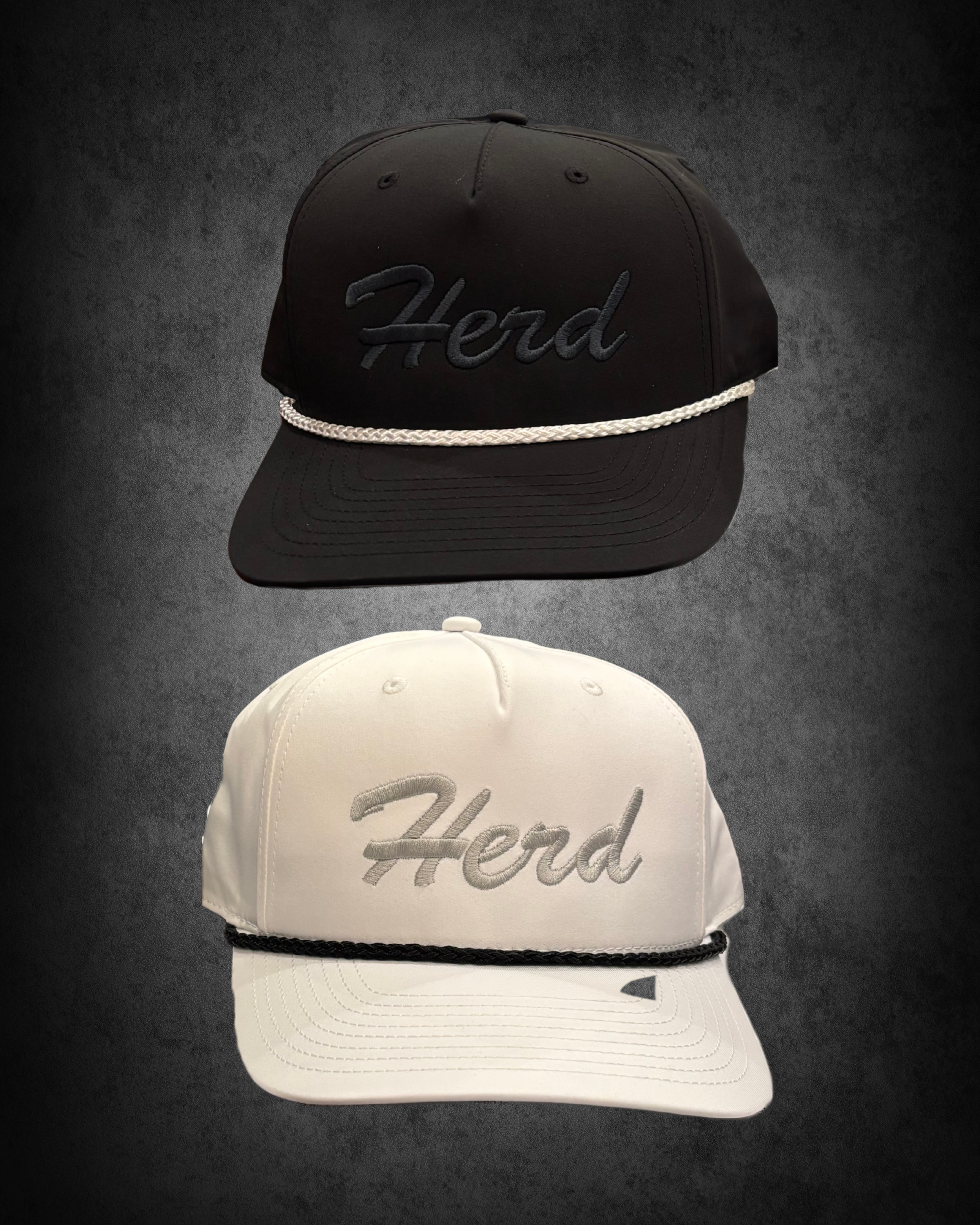 Two hats, one black with a silver chain and embroidery reading 'Herd' on the front, and one white with similar embroidered text, both displayed against a dark background.