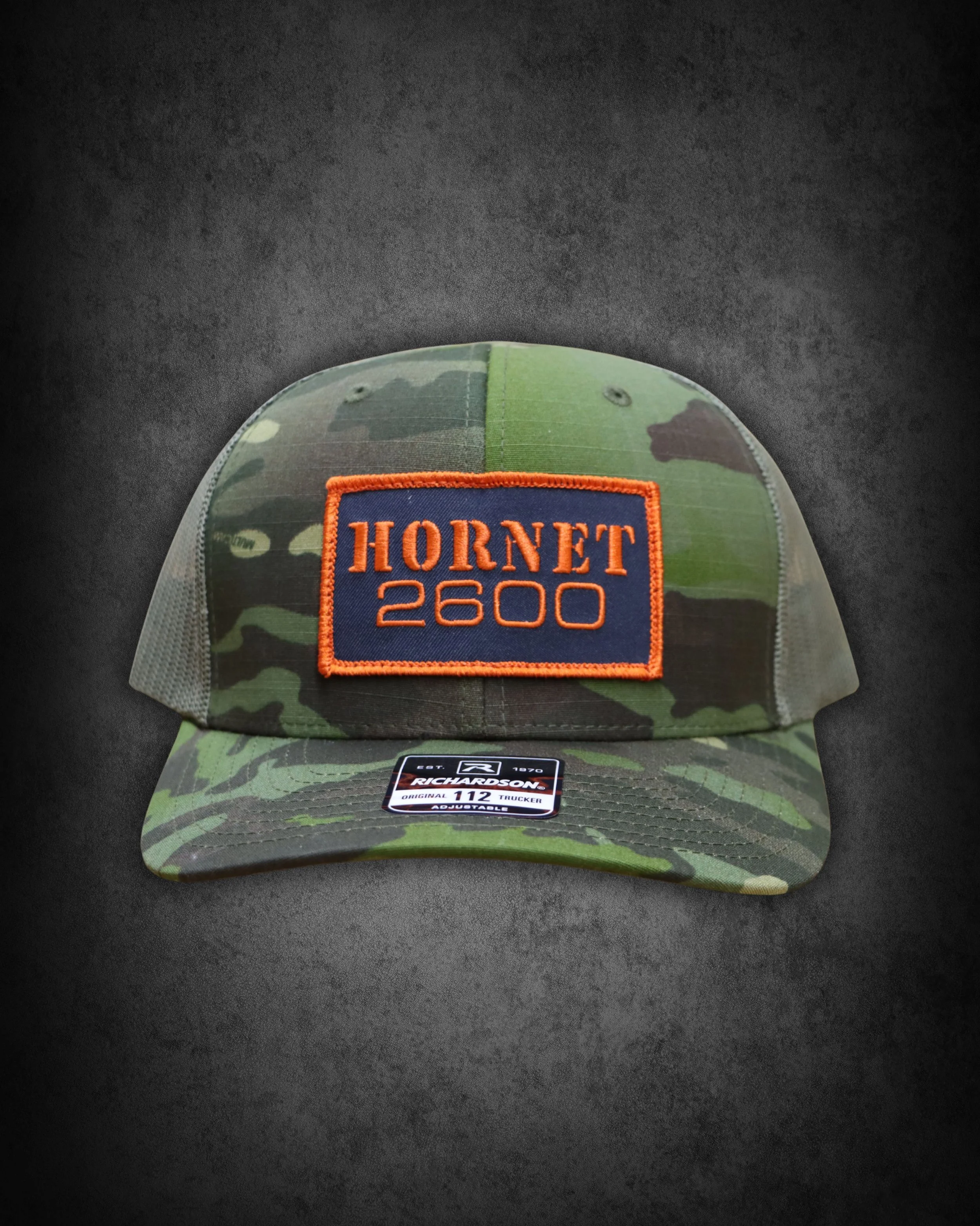 Camouflage baseball cap with orange embroidered patch reading 'Hornet 2600'.