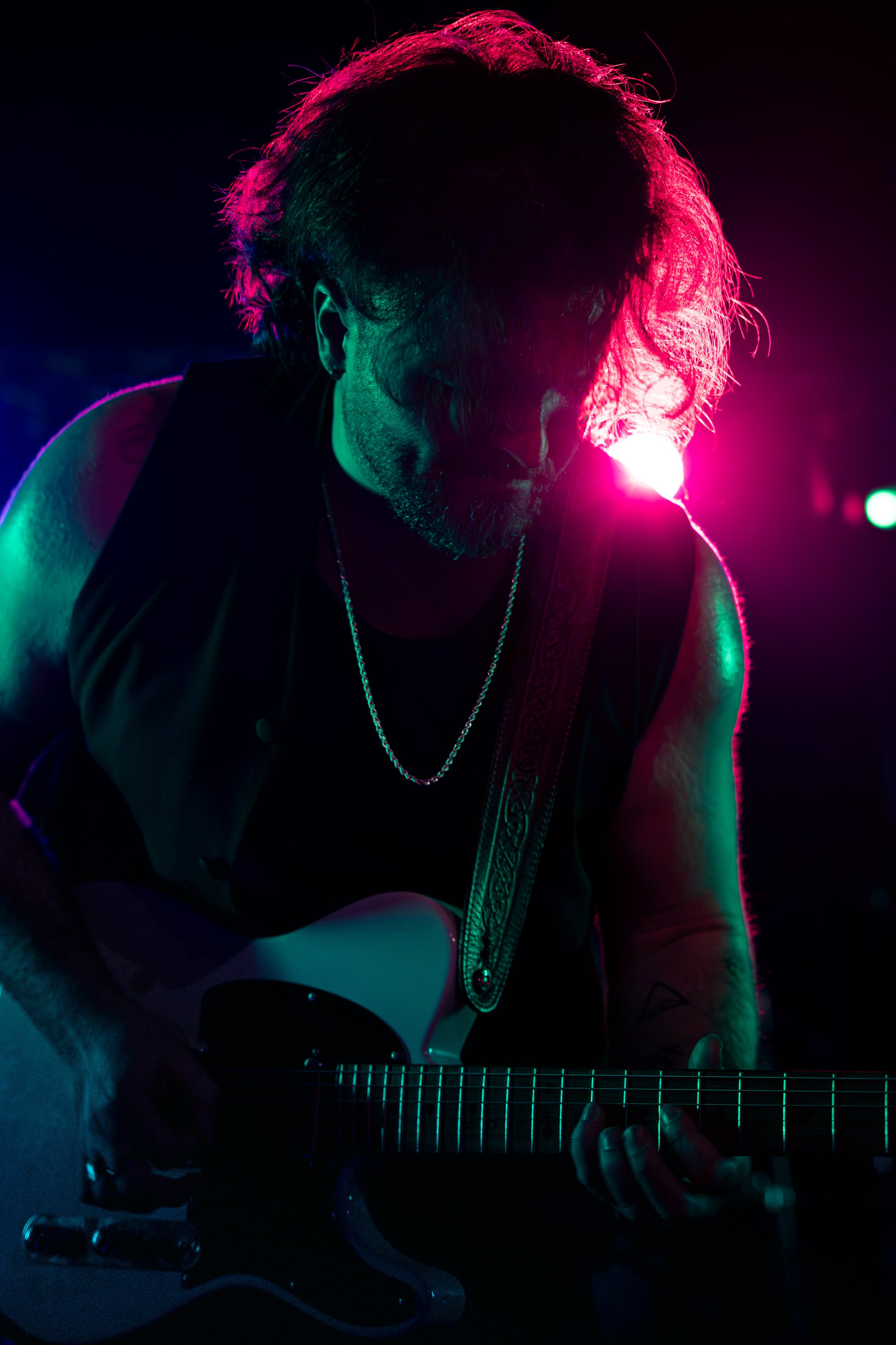 Guitarist playing in deep purple atmospheric lighting, showcasing the Frisson Media dark mode aesthetic. Professional musician portrait.