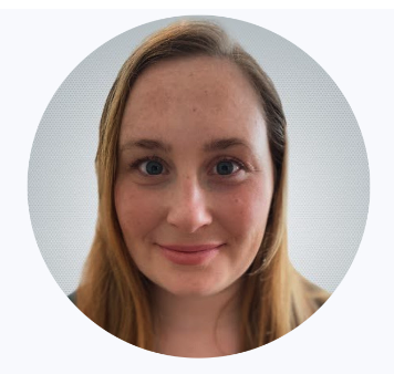 A close-up portrait of a young woman with long blonde hair, blue eyes, and fair skin, looking directly at the camera with a slight smile.