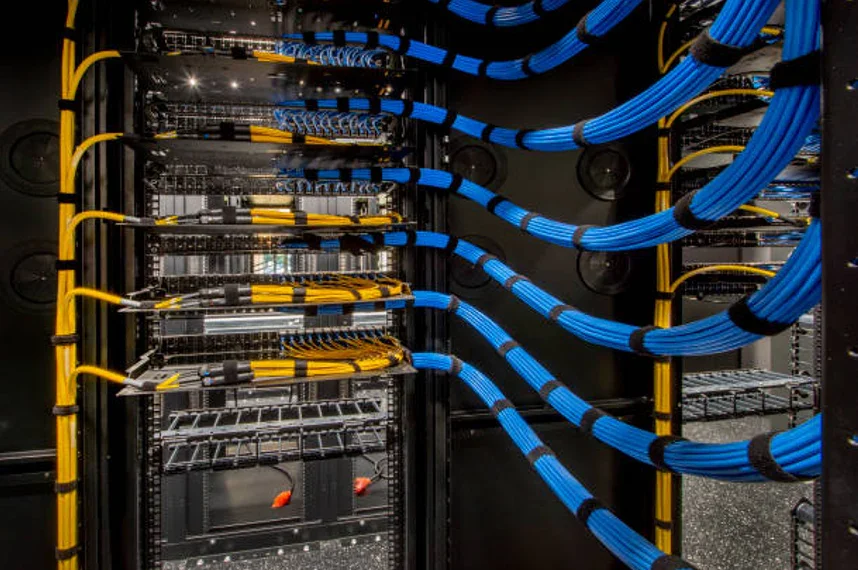 Server rack with blue and yellow network cables connected to equipment in a data center.