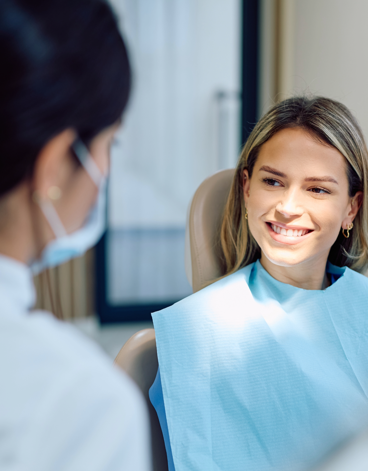 A woman in a dental chair smiling at a dentist during a dental appointment.