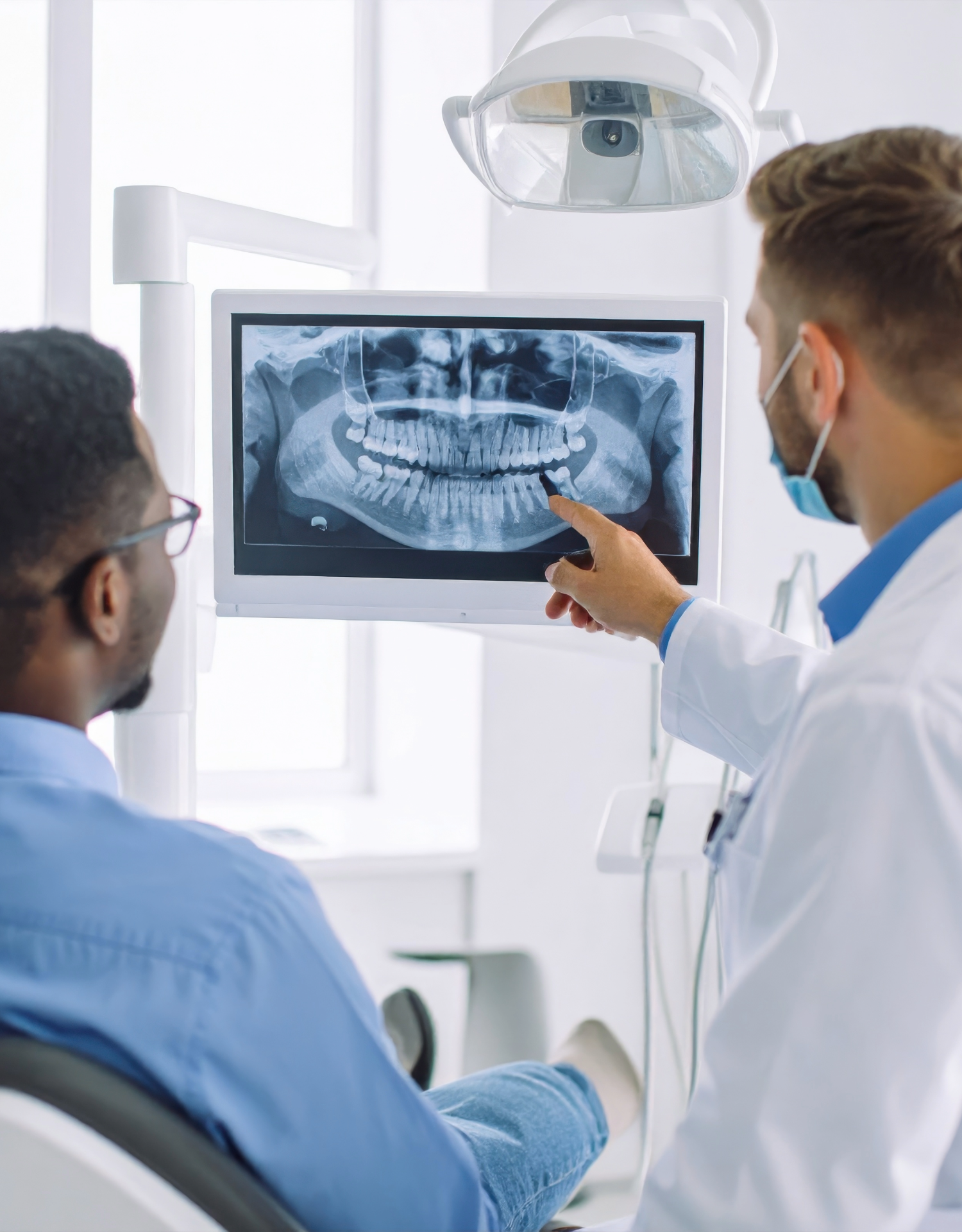 Dentist and patient examining a dental X-ray in a medical office.