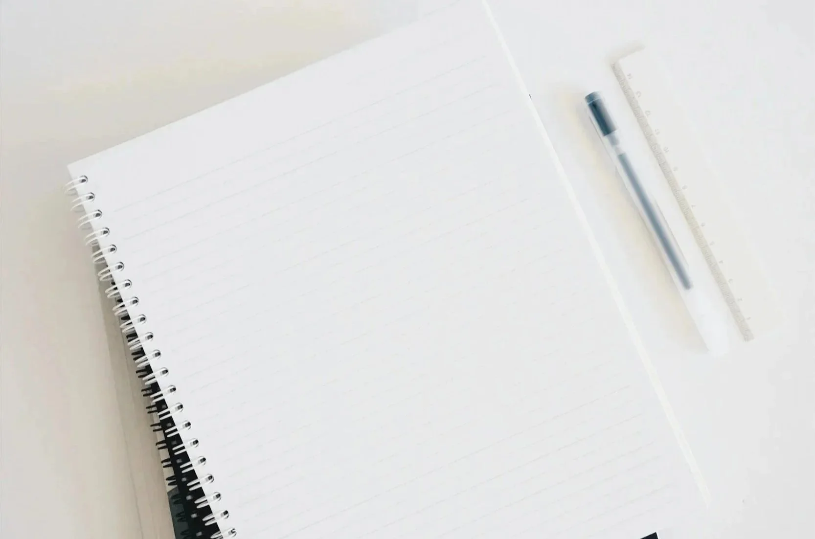 stack of notebooks with a pen and ruler to the side