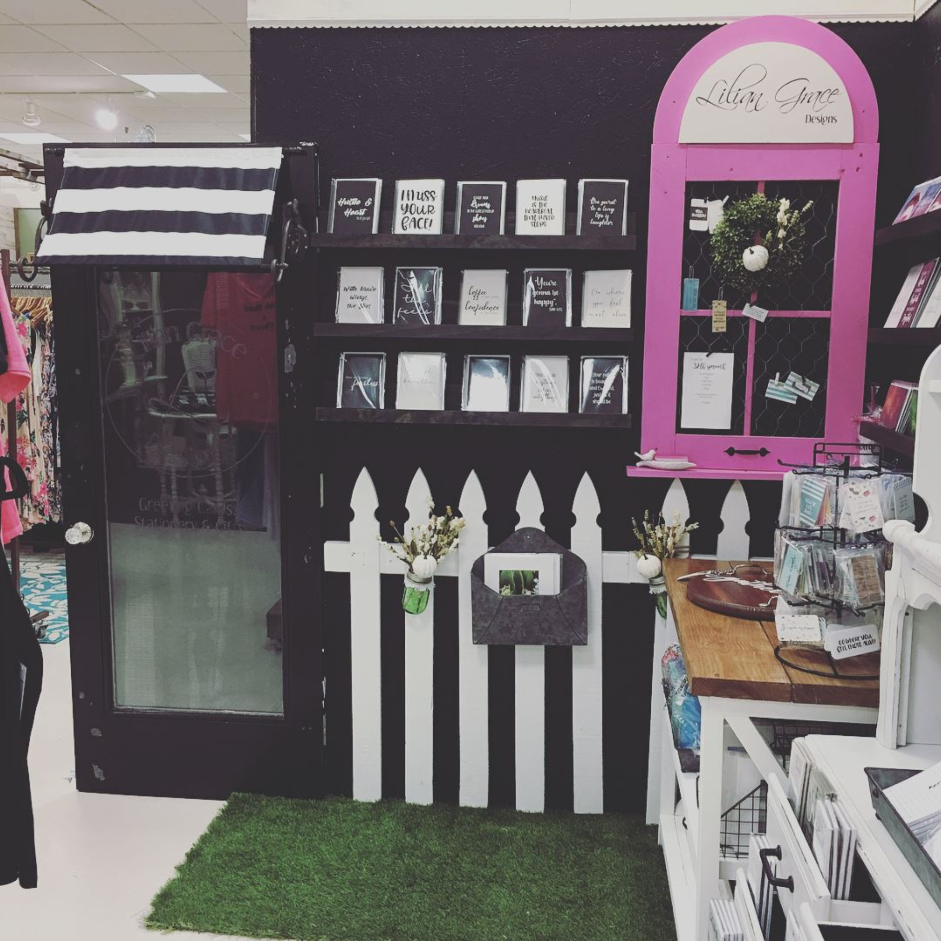 wall of greeting cards with white picket fence and a hot pink window
