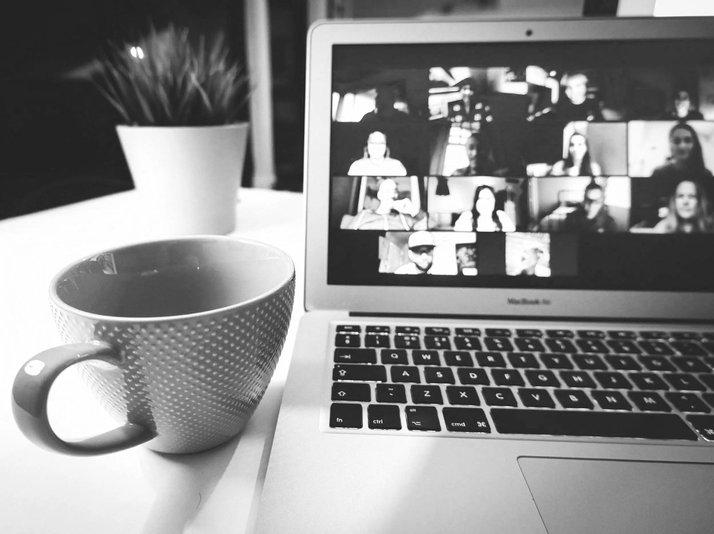 laptop with zoom meeting screens and a mug next to it