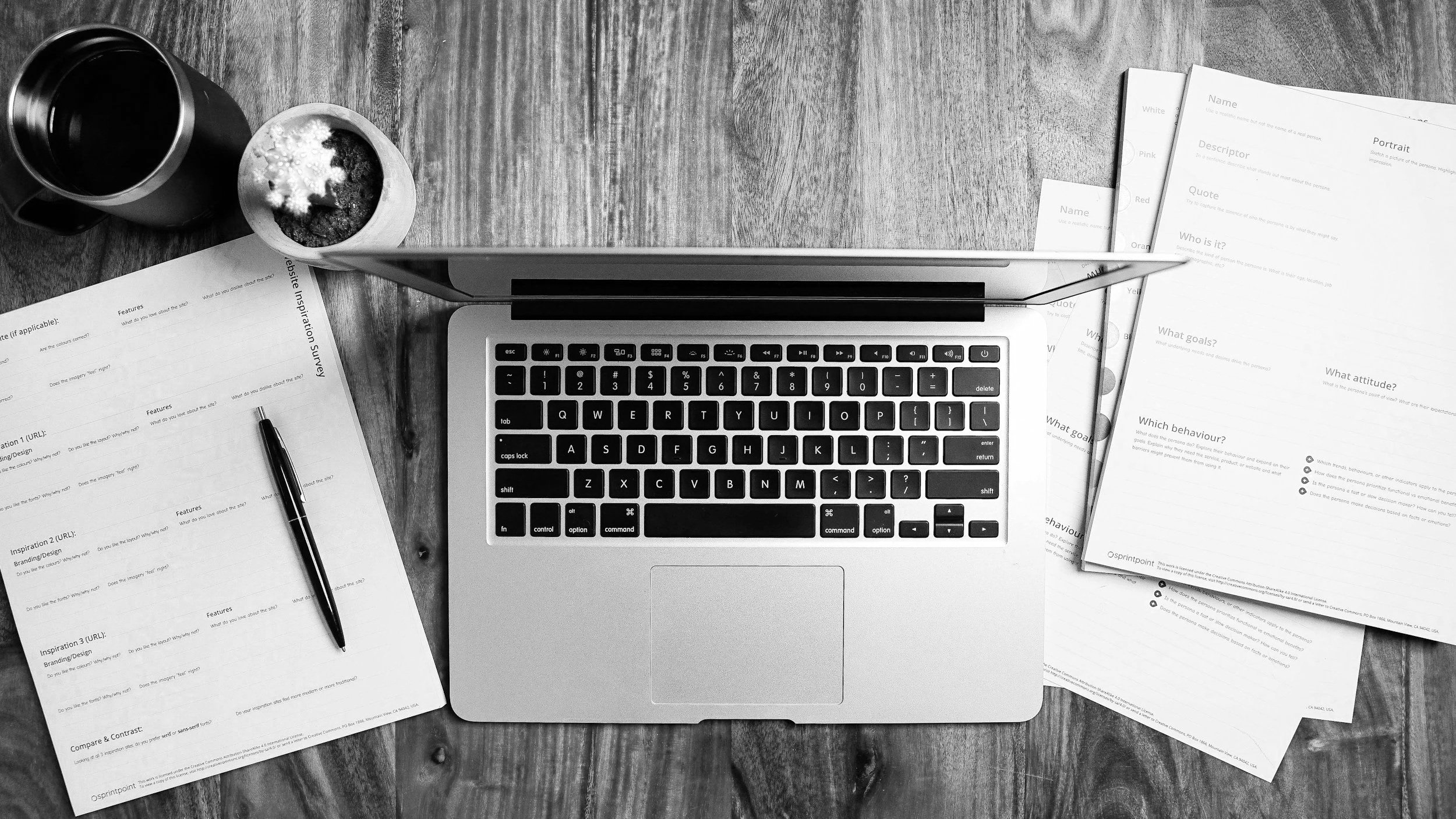 laptop and a stack of printed papers