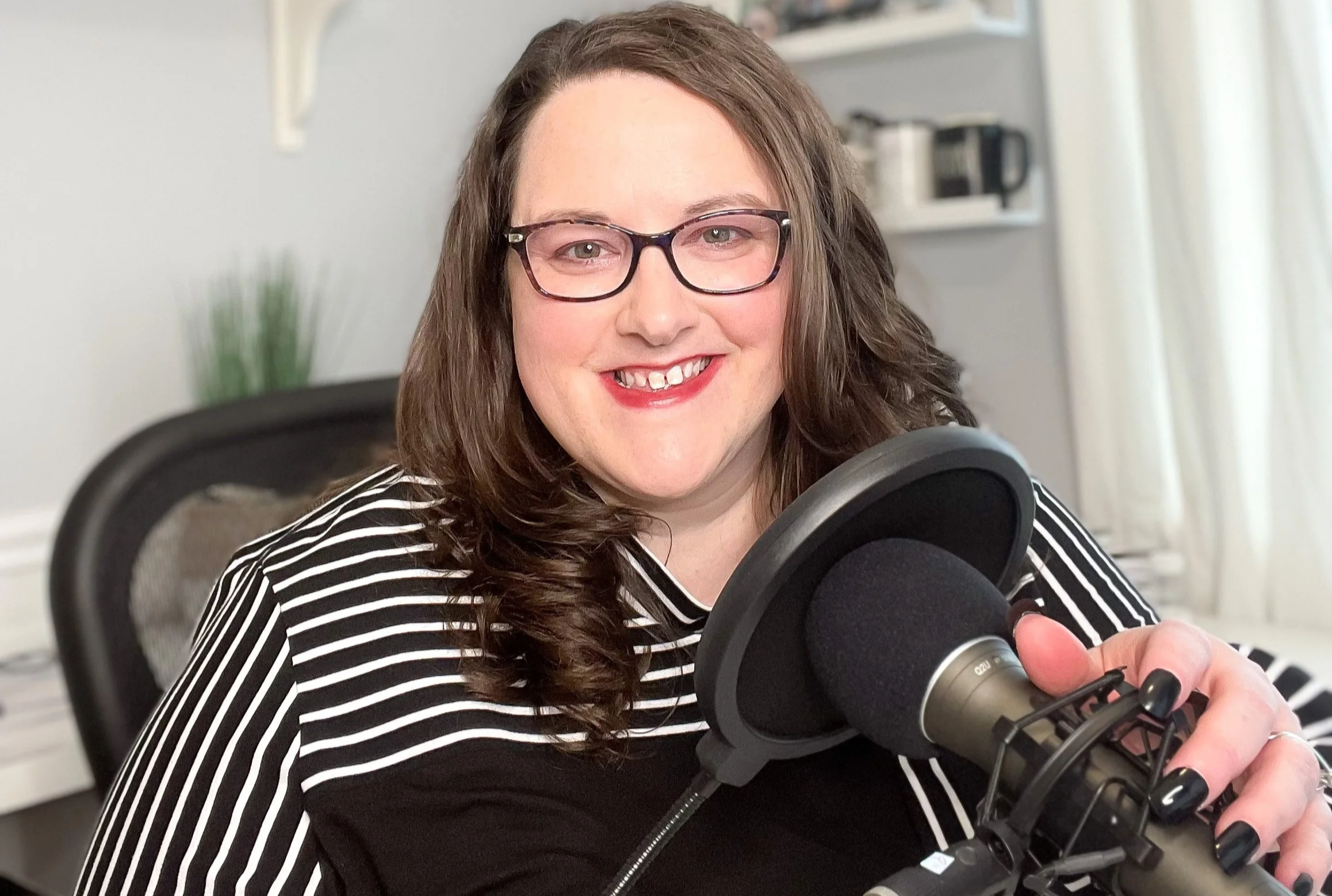 Shonda sitting at her desk with a podcast microphone