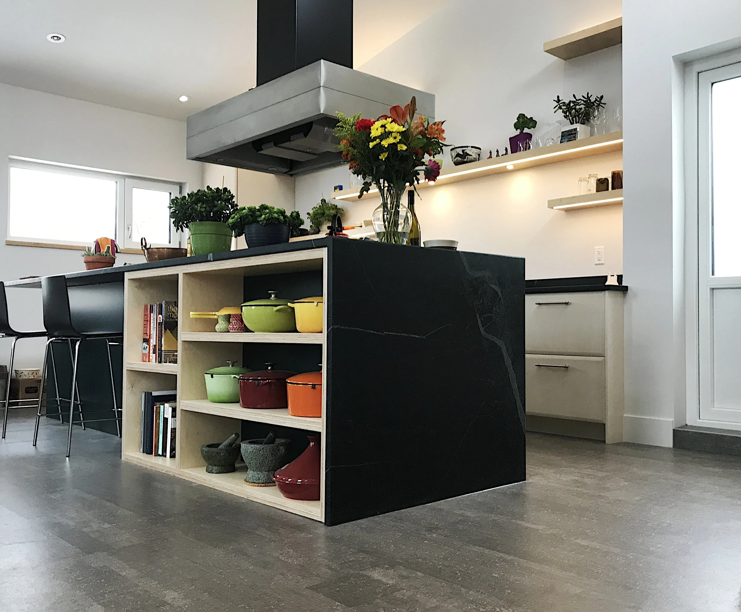 A modern kitchen with floating shelves and soapstone countertop