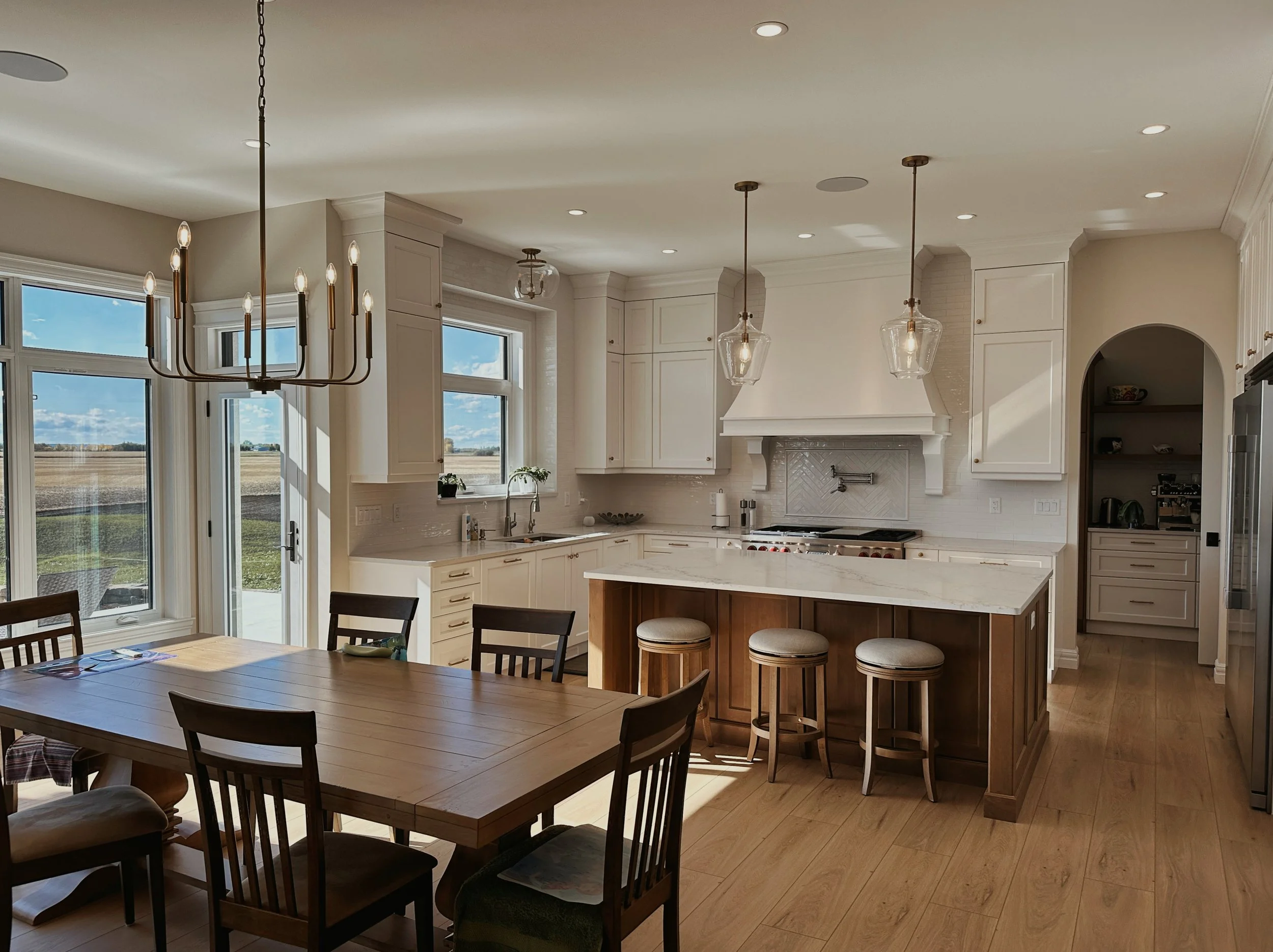 A large Kitchen and eating area with white cabinets.