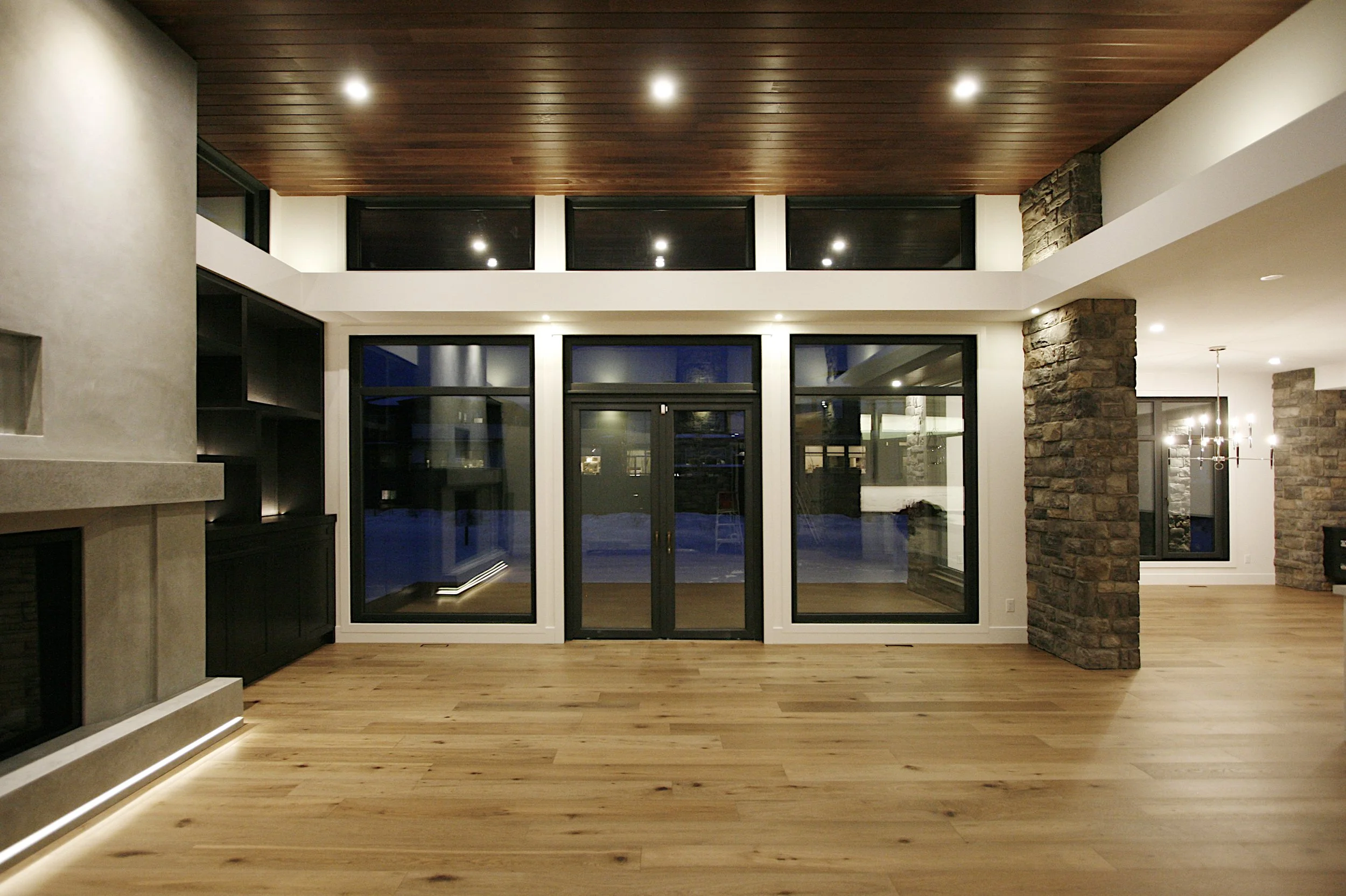 A living room with large windows, wood ceiling and large fireplace