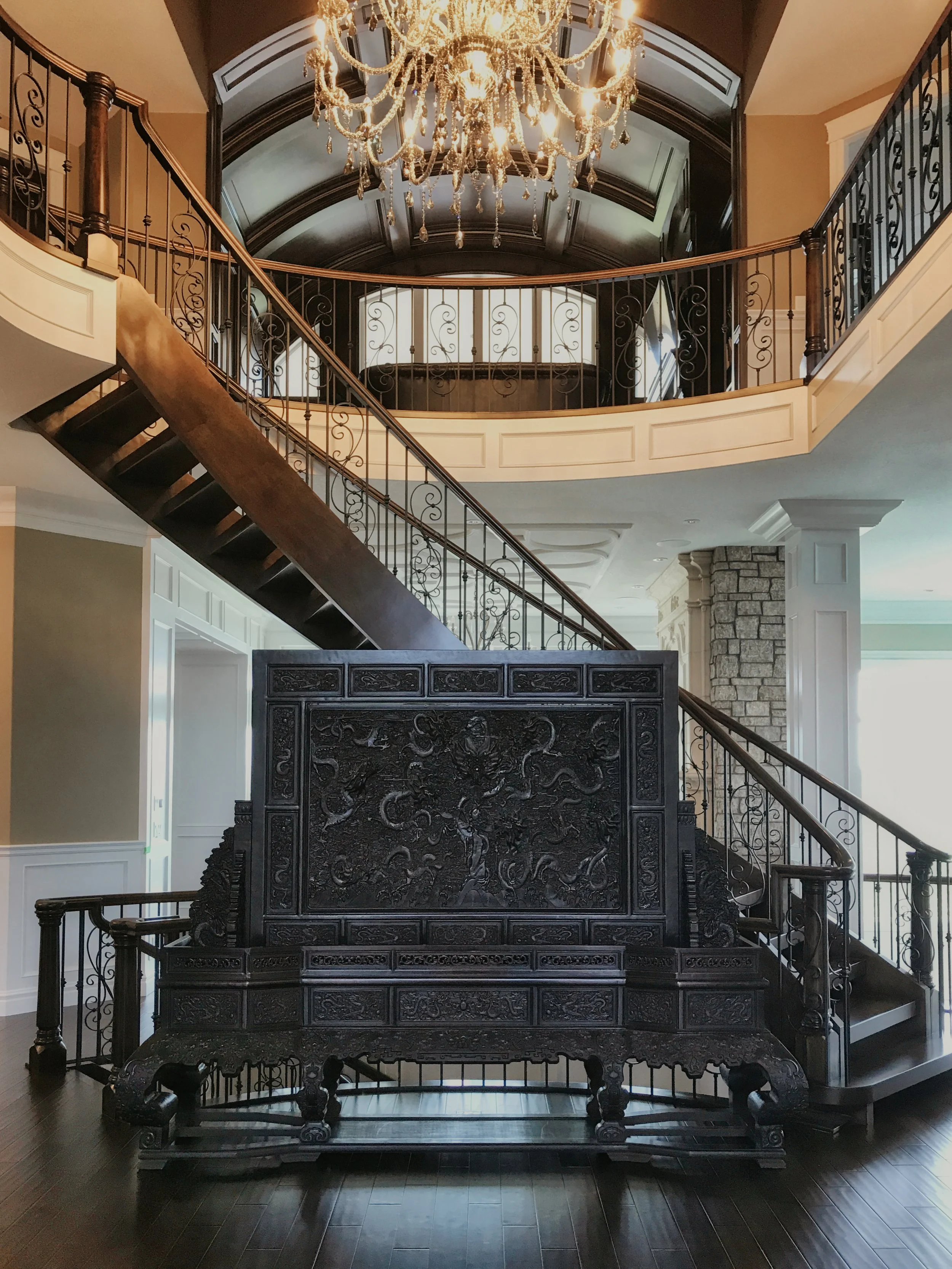Upscale entryway with curved staircase, chandelier, and artistic wood screen 