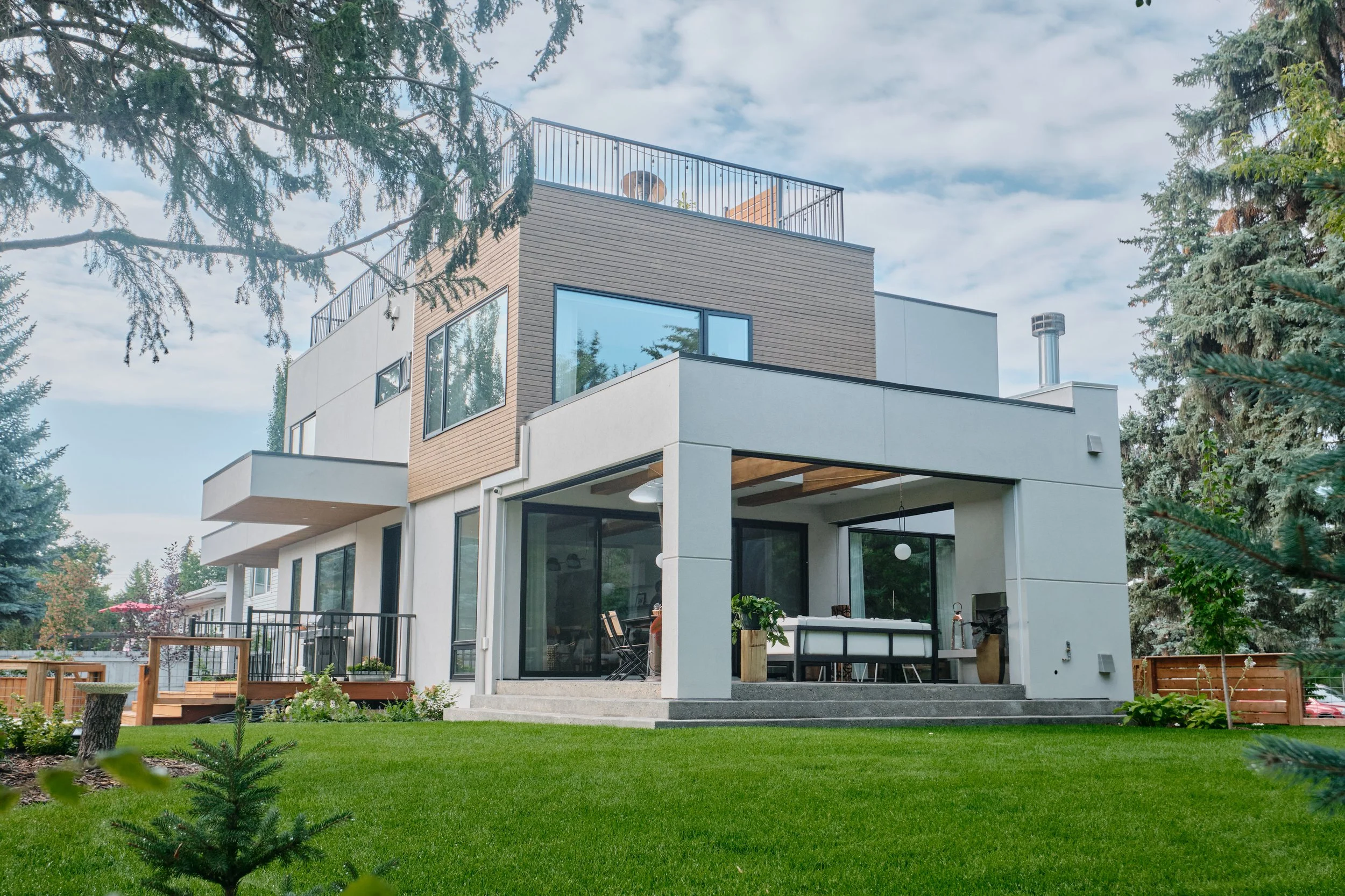 Contemporary multi-story home with rooftop terrace, wood paneling, and outdoor patio in Edmonton.