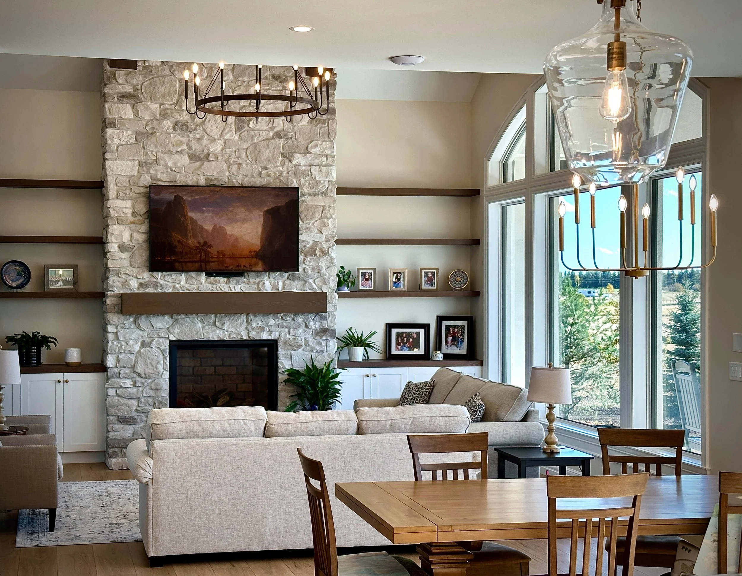 A living room with a stone fireplace and floating shelves
