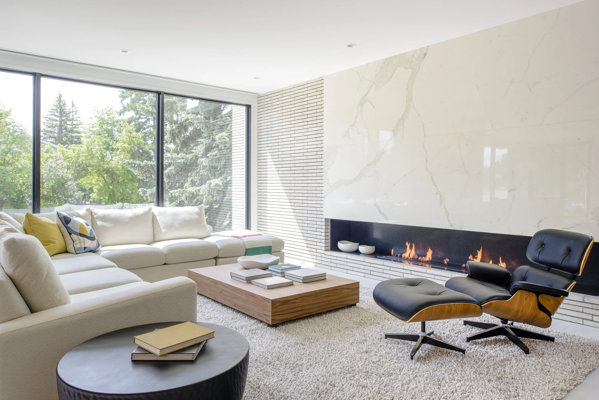 A living room with large windows and a long linear fireplace