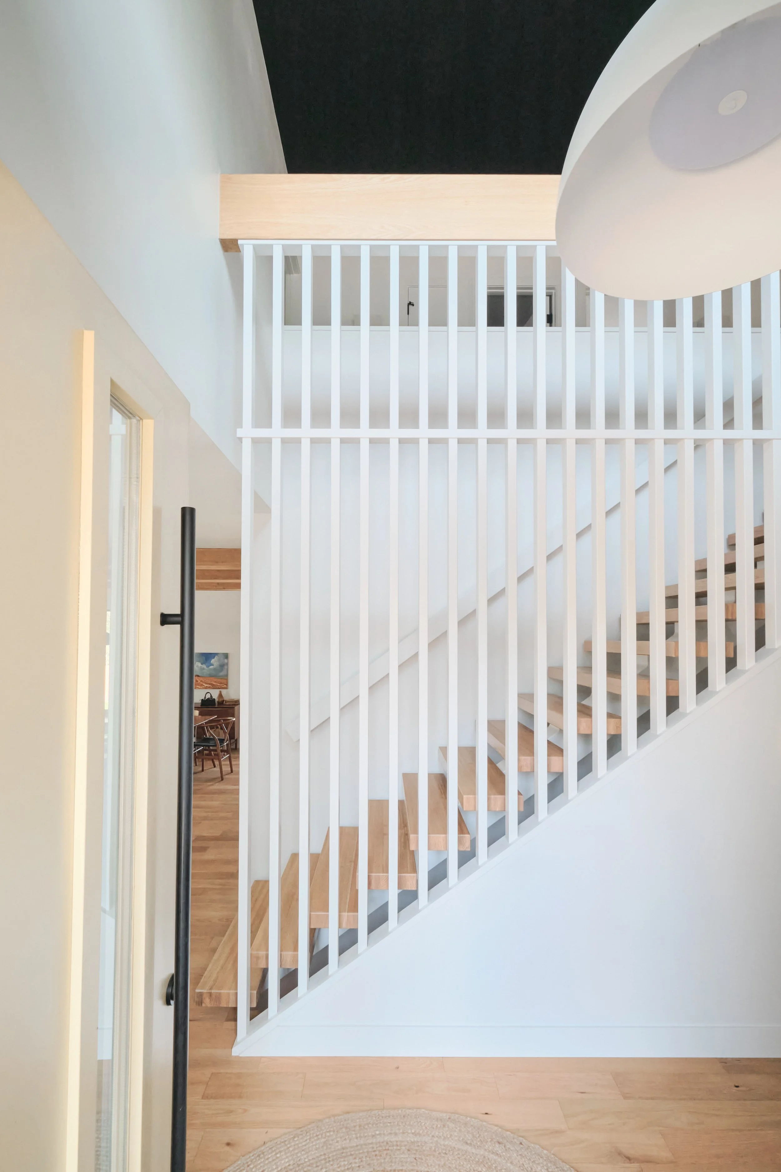 Mono Stringer staircase with natural wood treads and white walls.