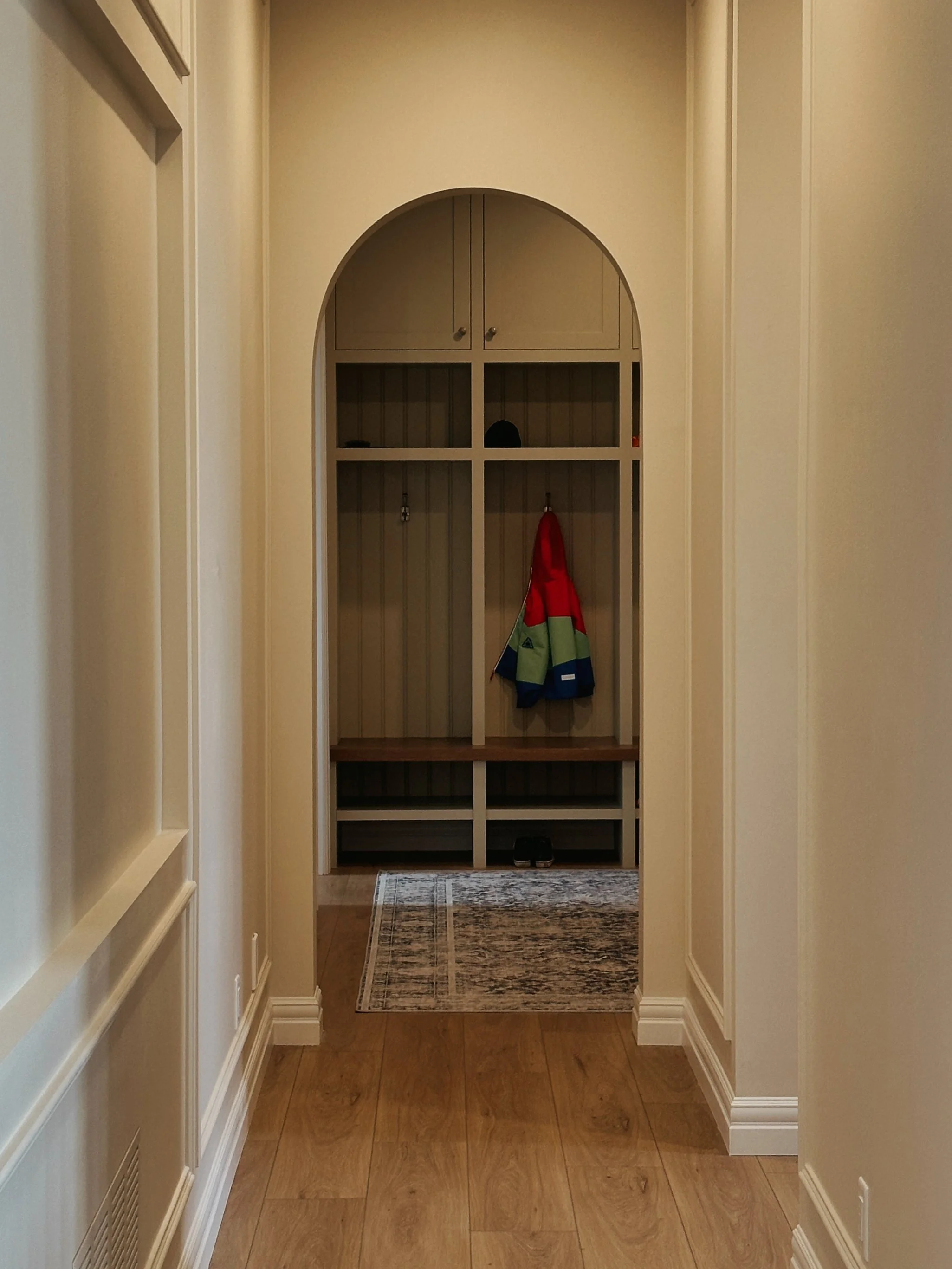 An arched door way going into a mud room with custom lockers